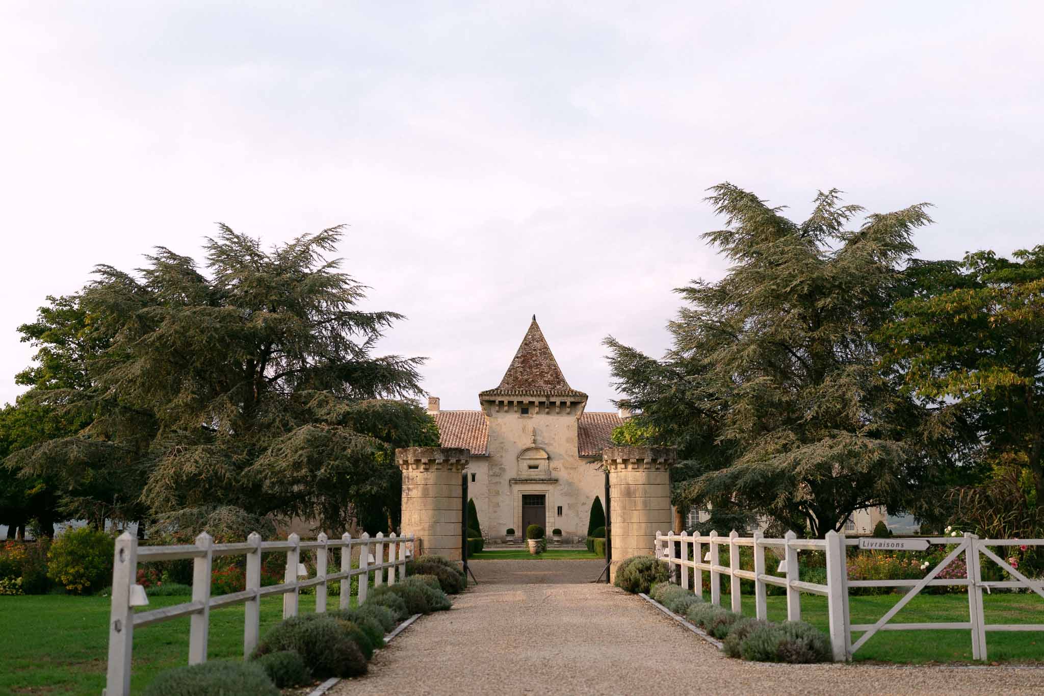 Chateau gatehouse with twin crenellated stone towers and conical turret on gravel driveway
