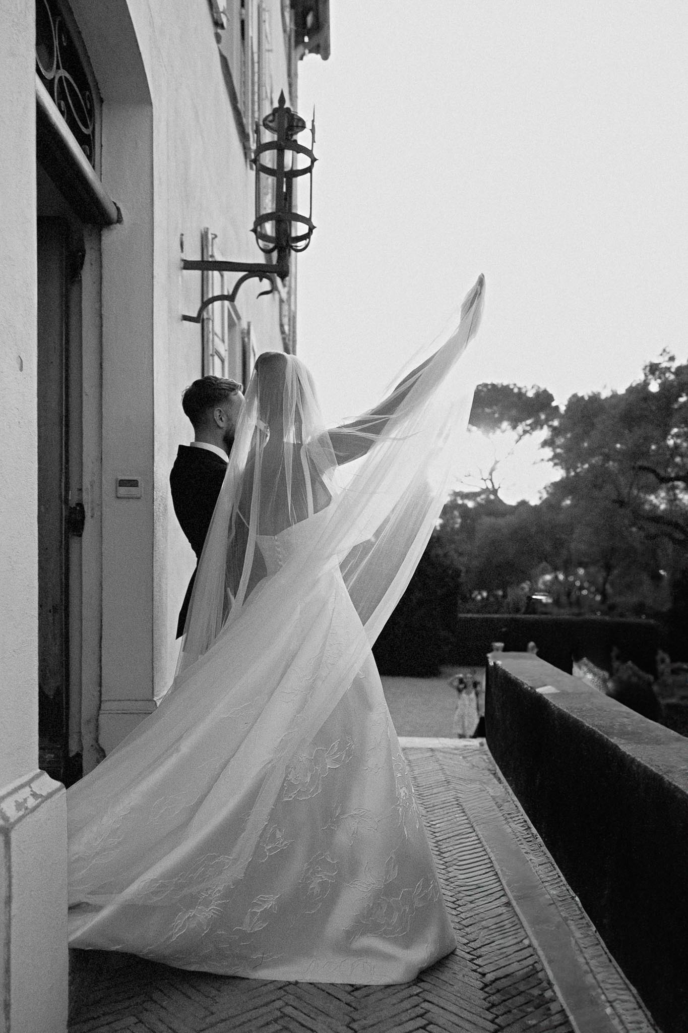 Bride and groom portrait with flowing cathedral veil on Mediterranean terrace