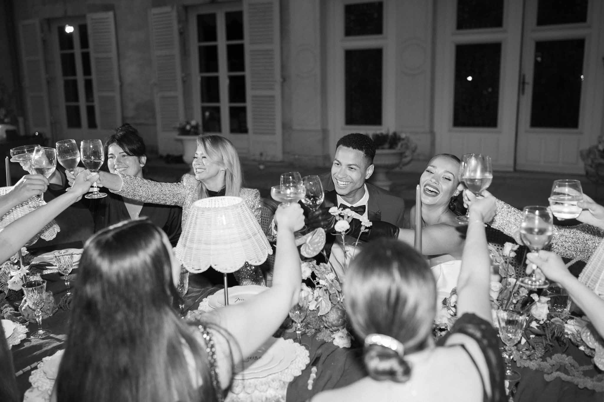 Bride and groom toasting with guests at outdoor reception dinner table at classic venue