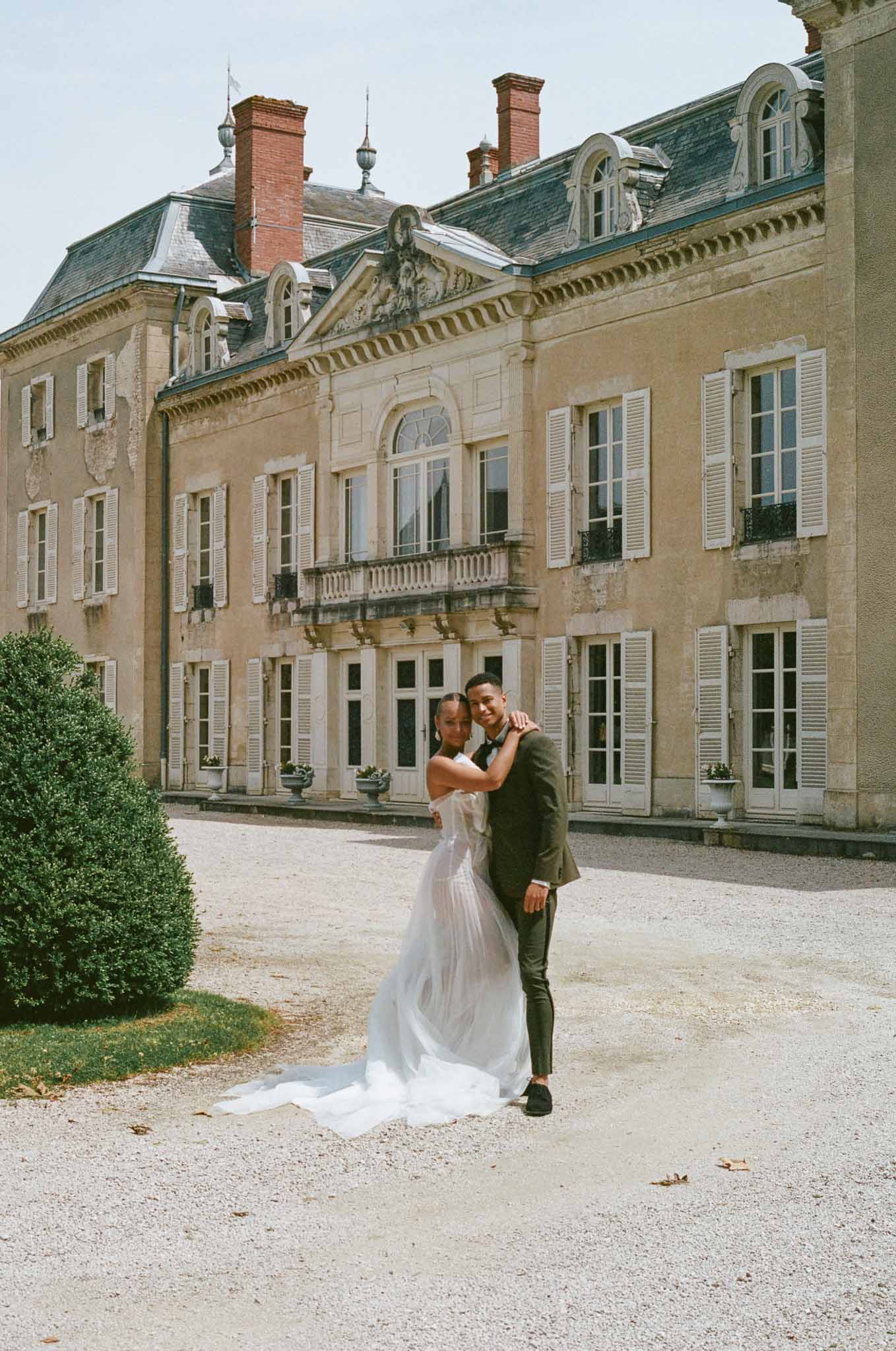 Bride and groom posing together in château courtyard for formal wedding portrait