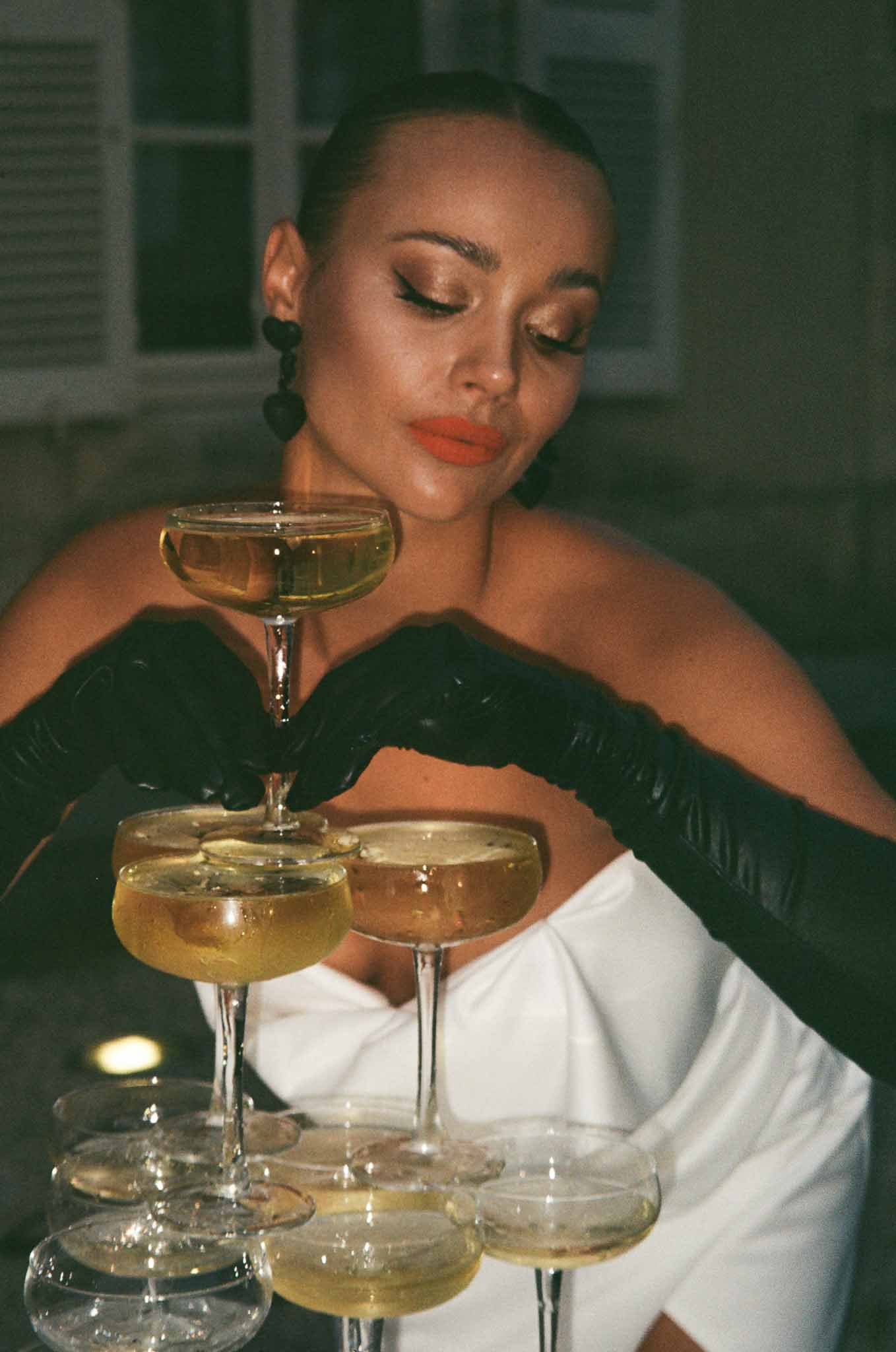 Woman holding champagne coupes at wedding reception with moody interior lighting