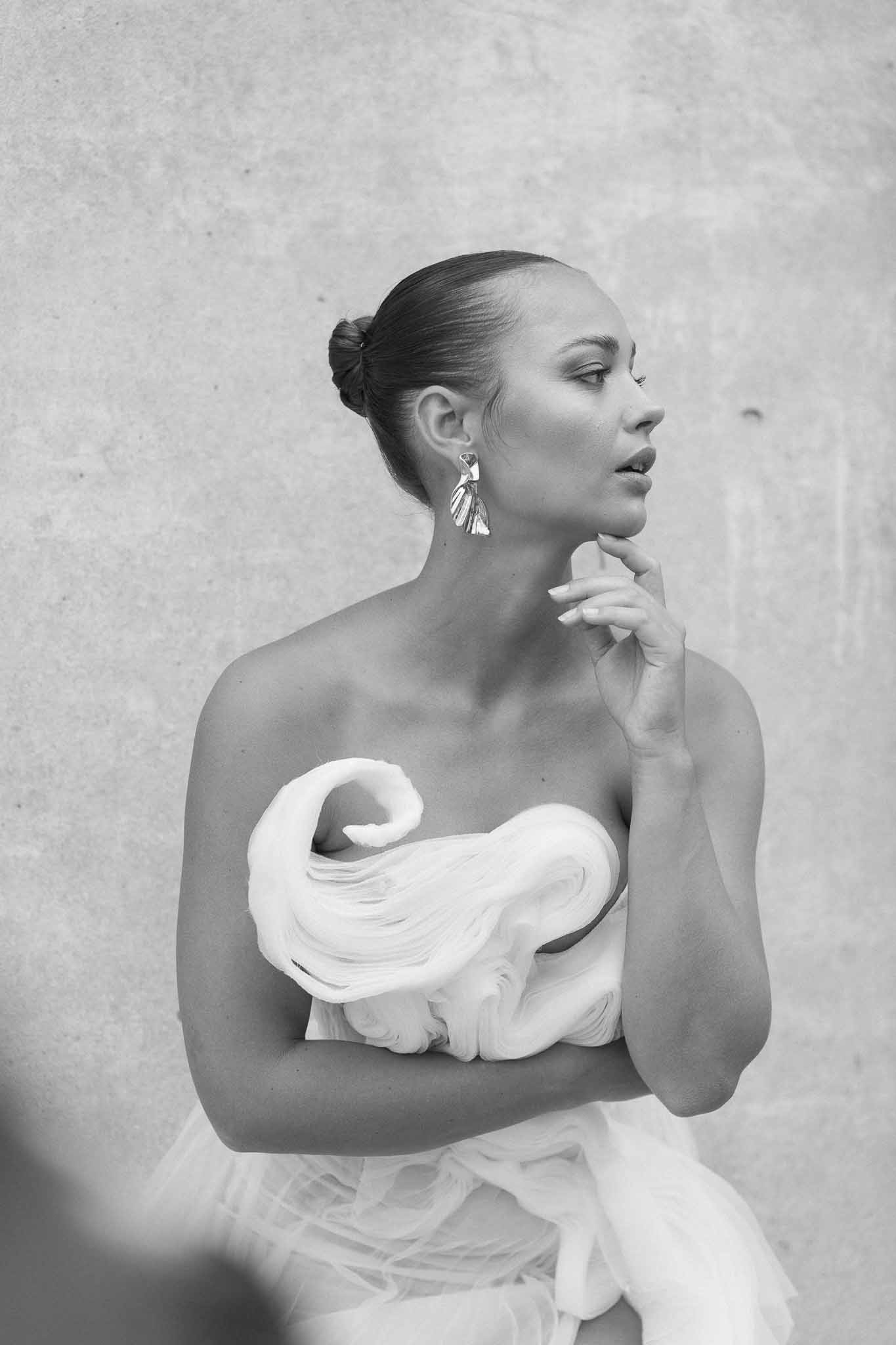 Black and white bridal portrait showing bride in profile wearing strapless dress with geometric earrings