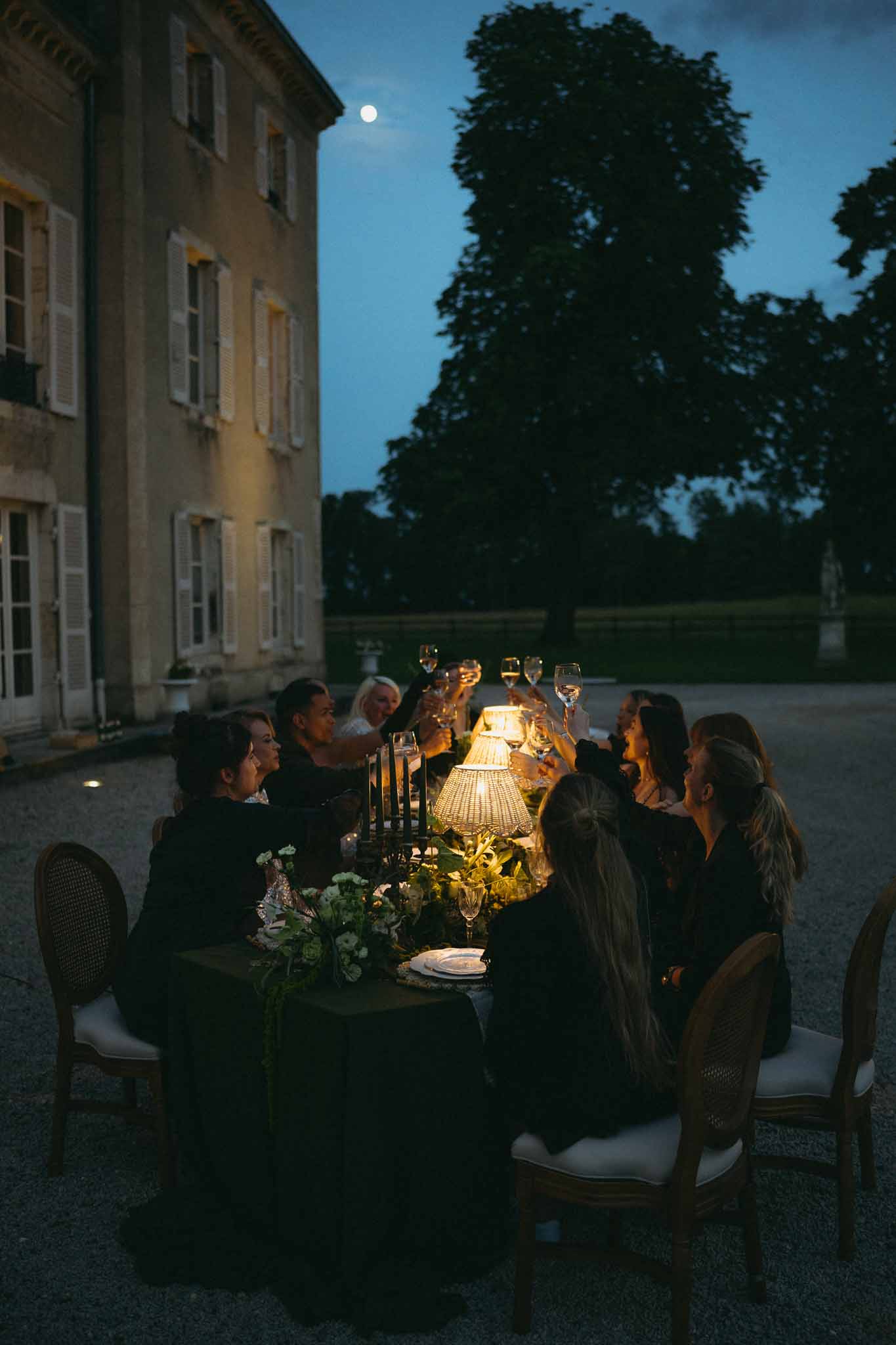 Evening reception dinner on historic manor house courtyard with candlelit table setting