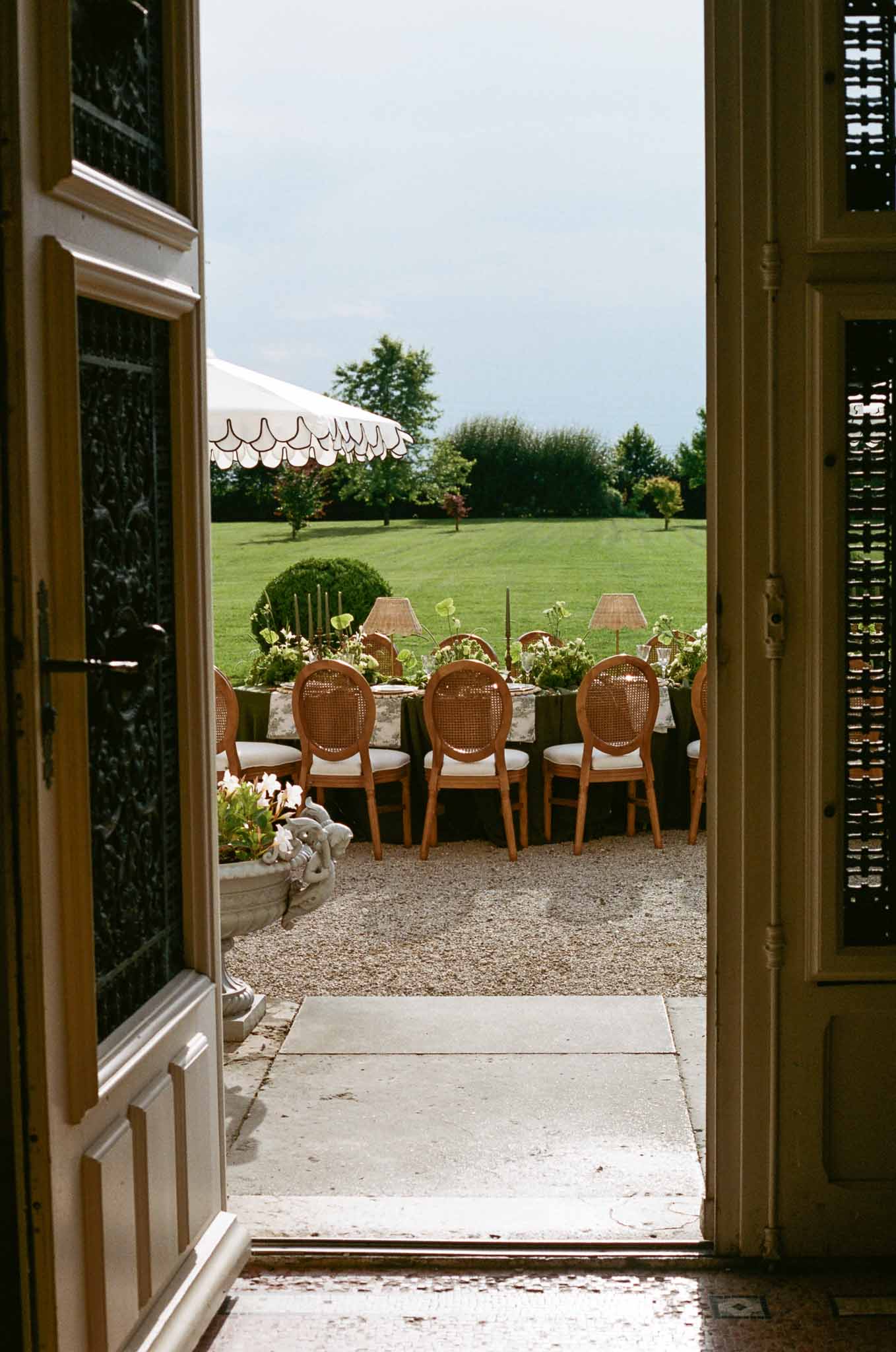 Reception table setup on terrace overlooking manicured gardens at French chateau wedding venue