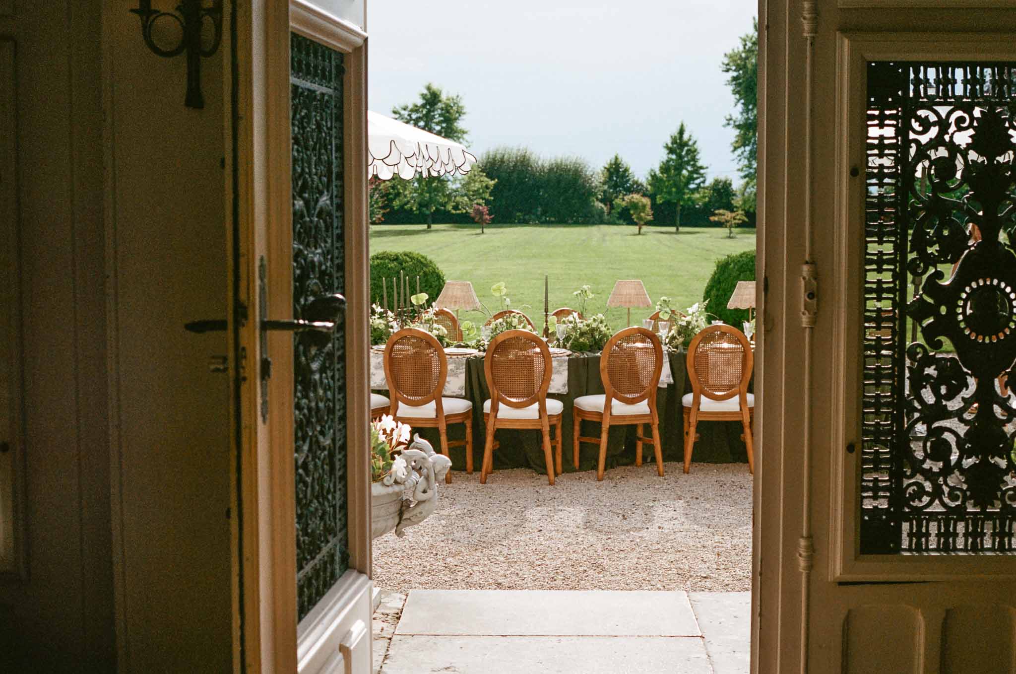 Outdoor reception terrace with formal garden views through French doors at elegant wedding venue