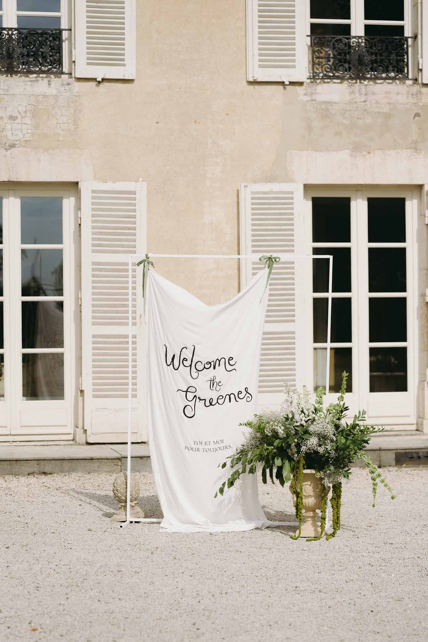 Wedding welcome sign with floral arrangement in Parisian courtyard with Haussmann architecture