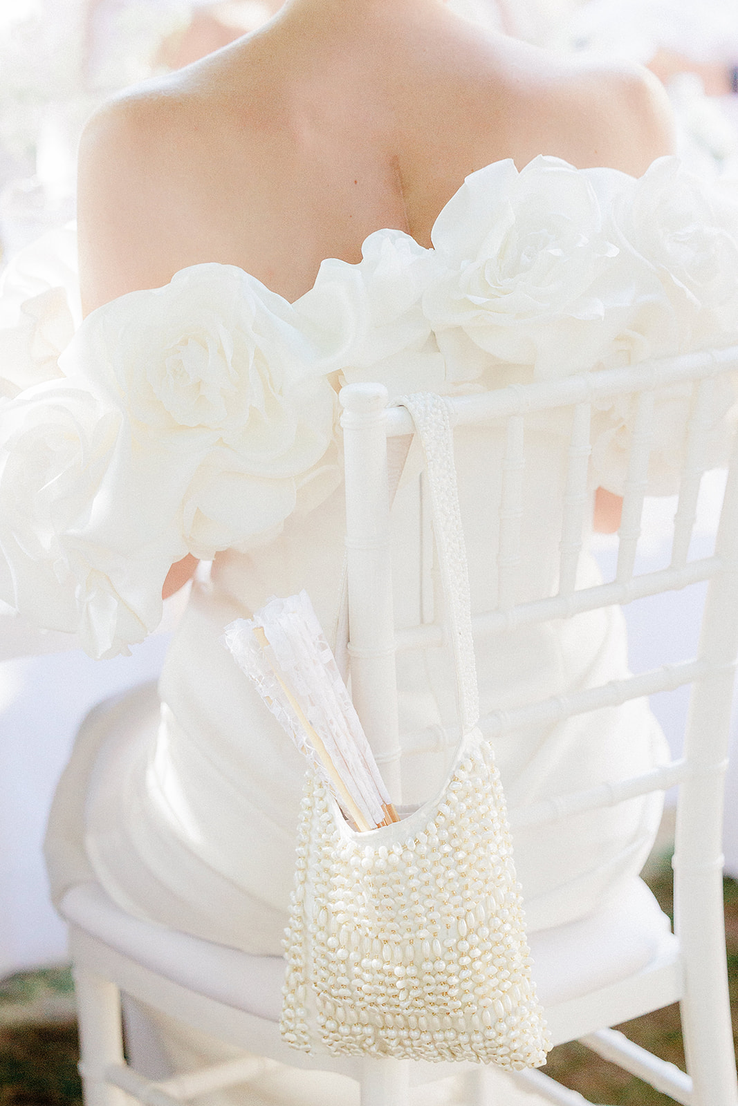 Bride holding ivory rose bouquet with pearl clutch at outdoor wedding ceremony