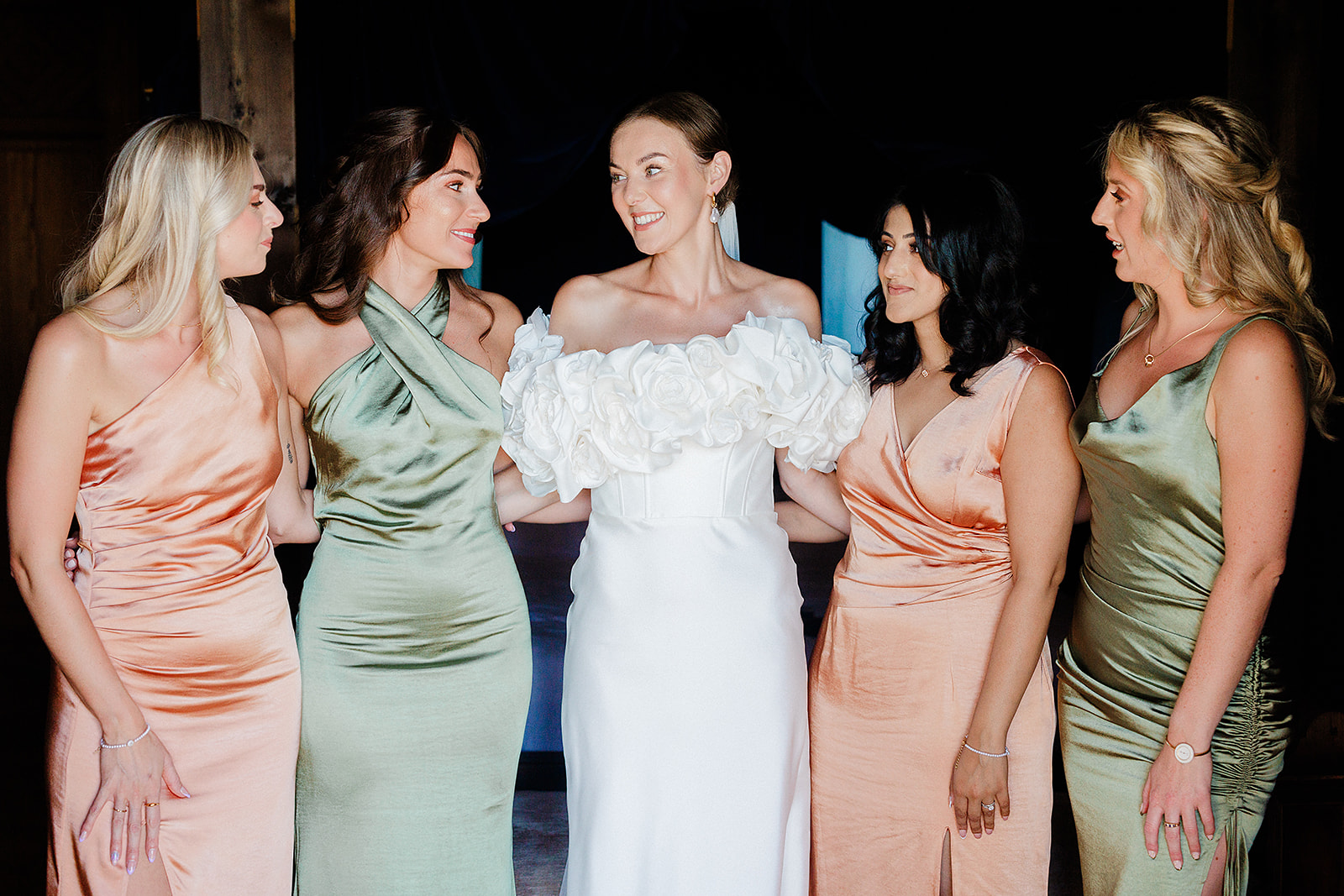 Bride with bridal party in jewel-tone dresses at indoor wedding reception
