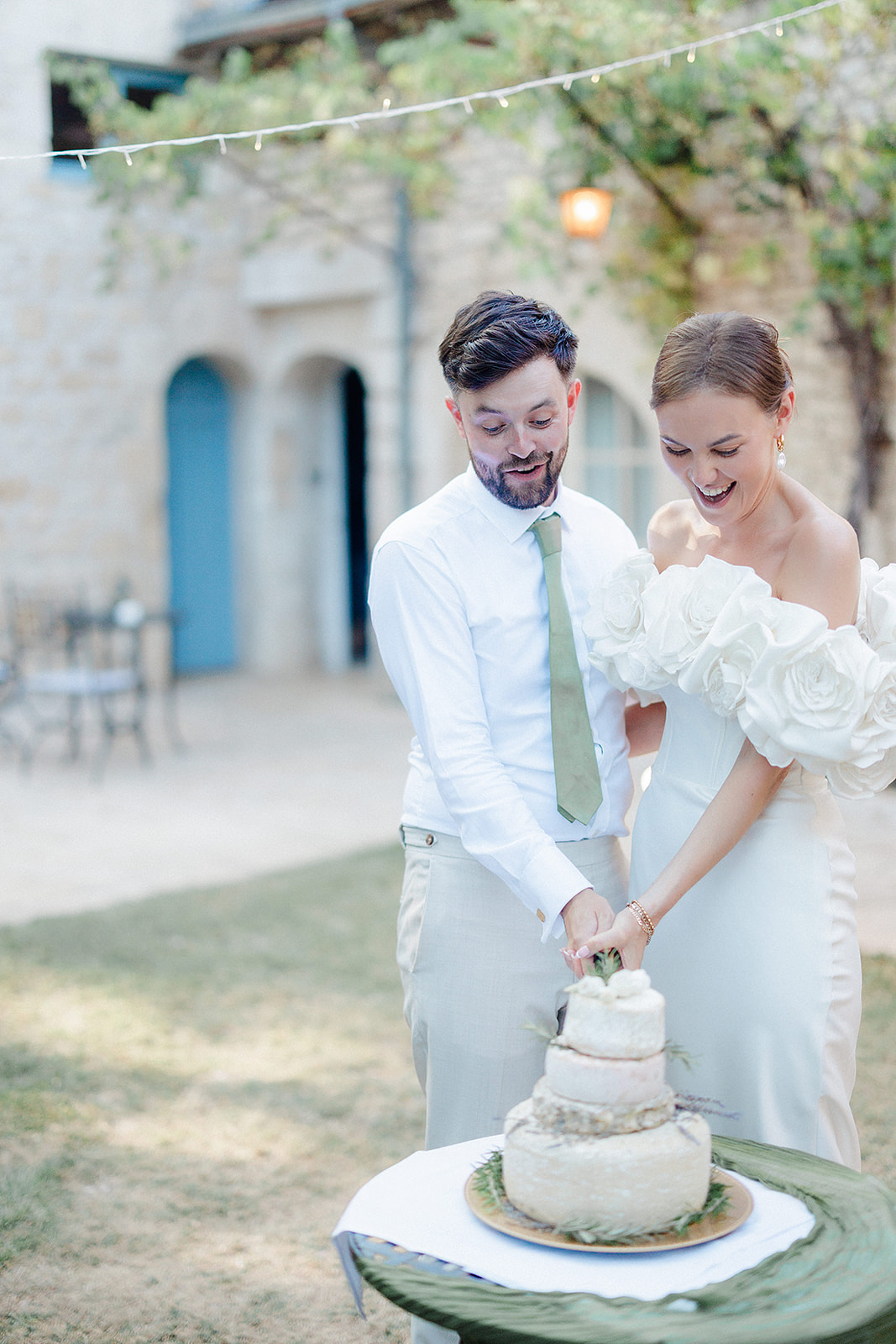 Bride and groom cutting three-tiered wedding cake during outdoor reception in Mediterranean courtyard