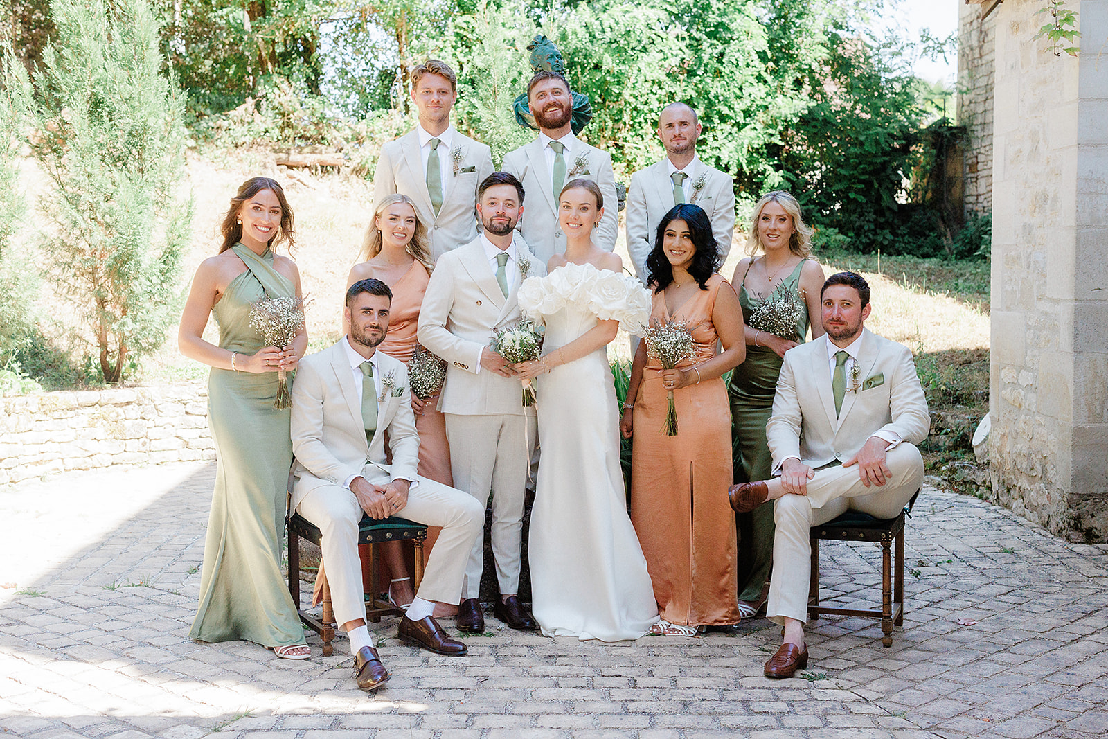 Bridal party group portrait in stone courtyard with ivy-covered walls