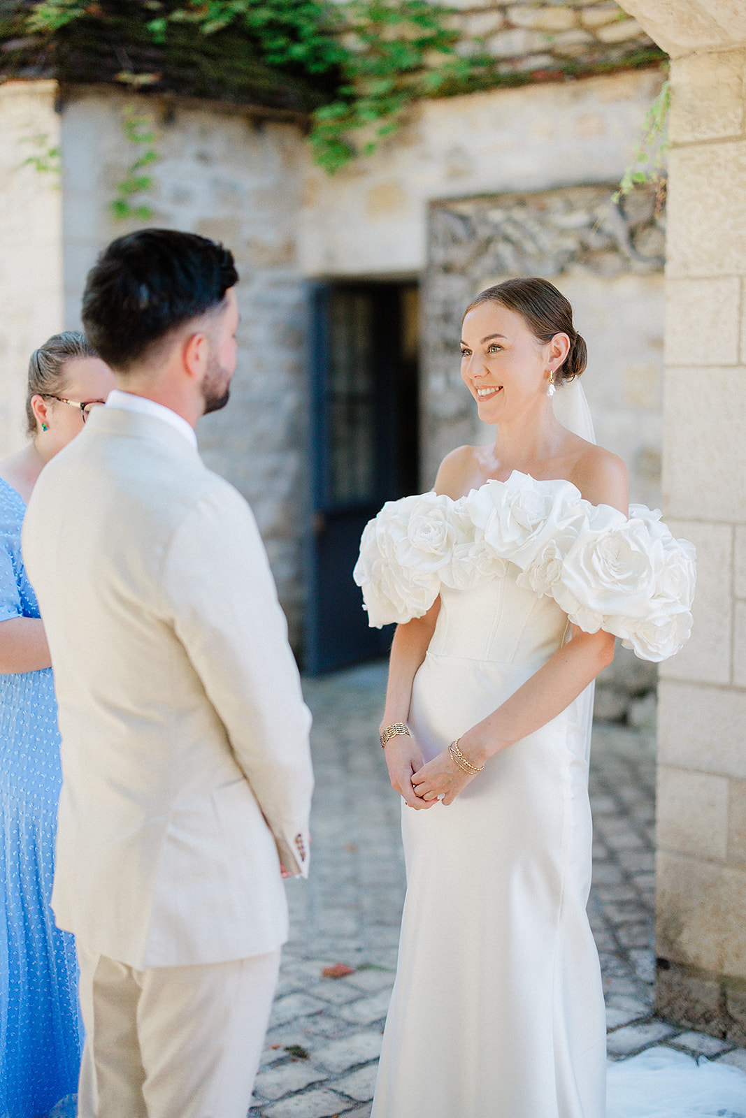 Bride and groom exchanging vows in stone courtyard with ivy-covered walls during outdoor wedding ceremony