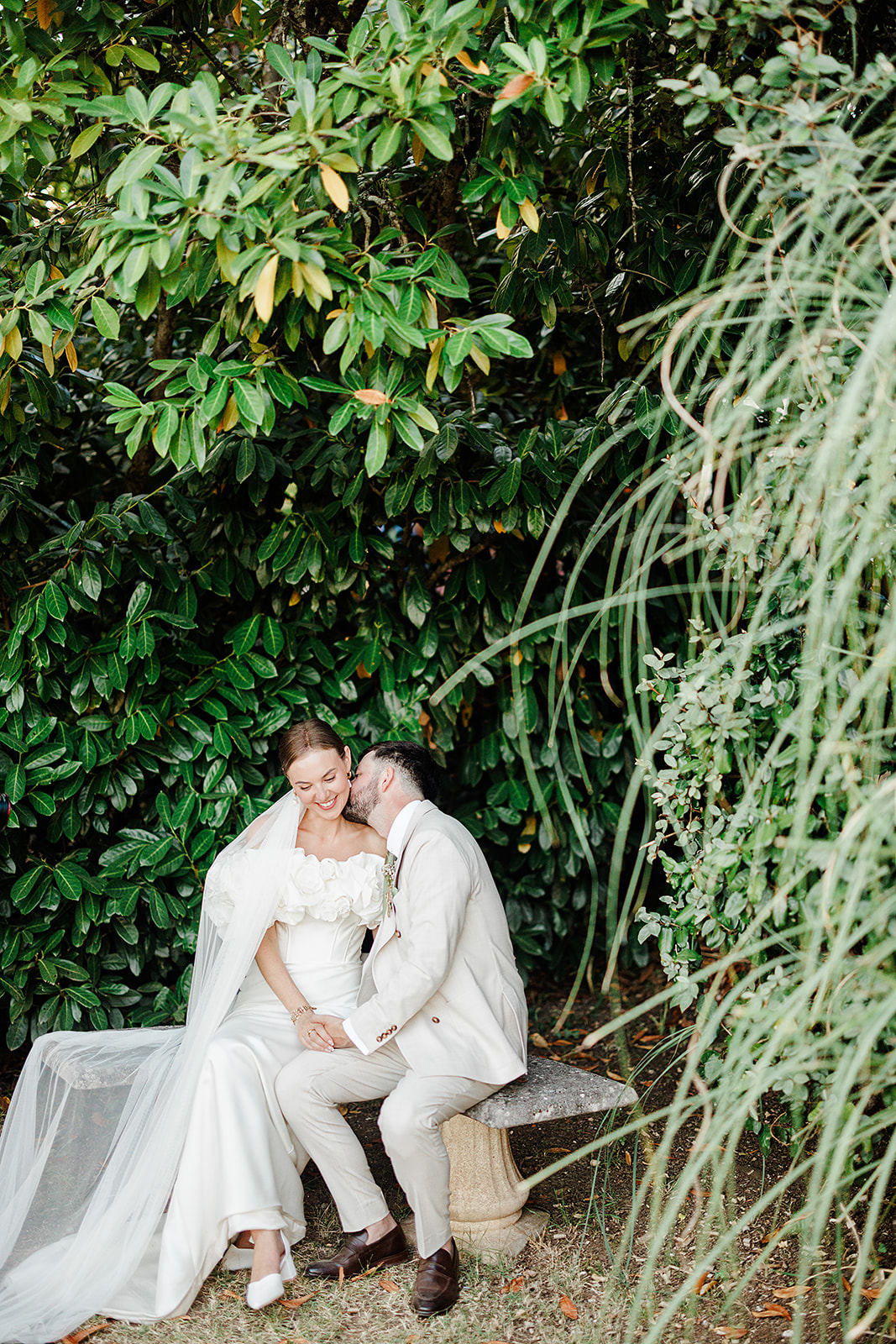 Romantic couple portrait on stone bench in lush garden setting with cascading greenery