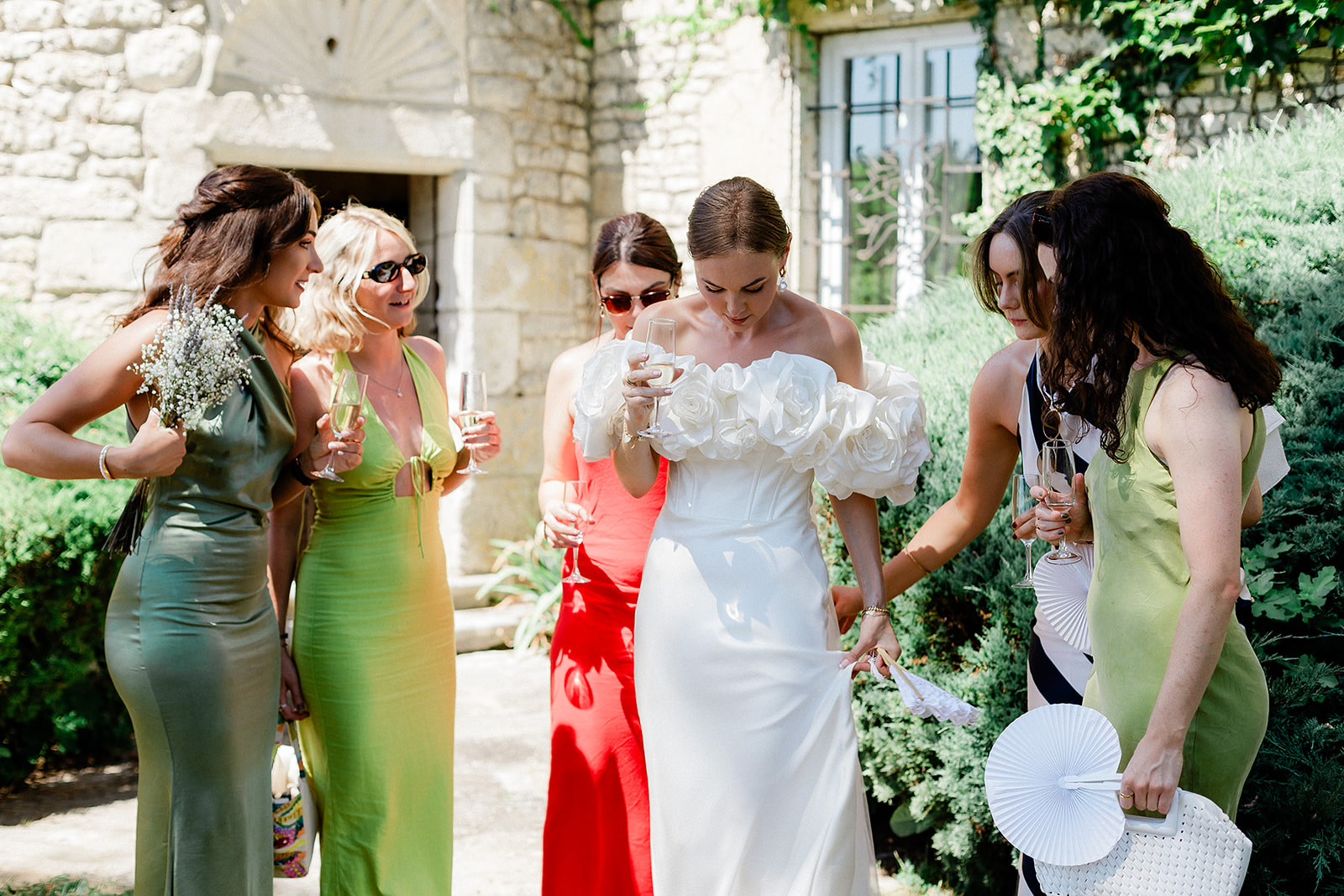 Bride with bridal party holding champagne in stone courtyard during cocktail hour