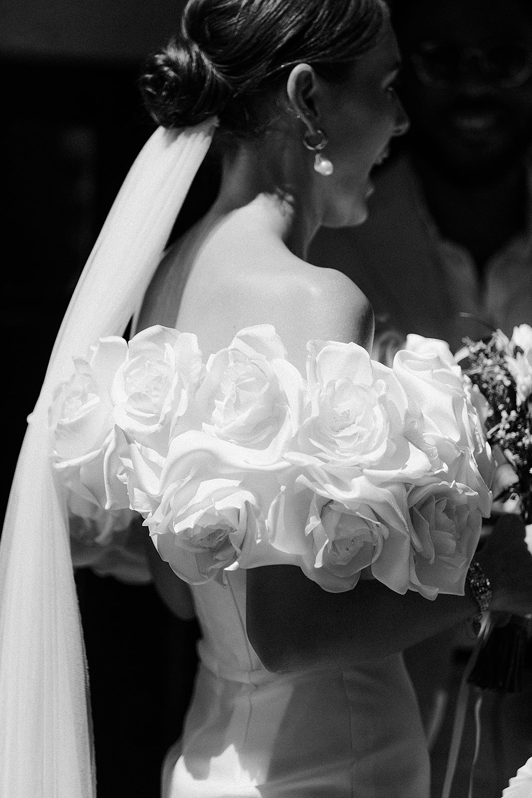 Black and white close-up of sculptural 3D rose applique bodice detail and pearl drop earrings
