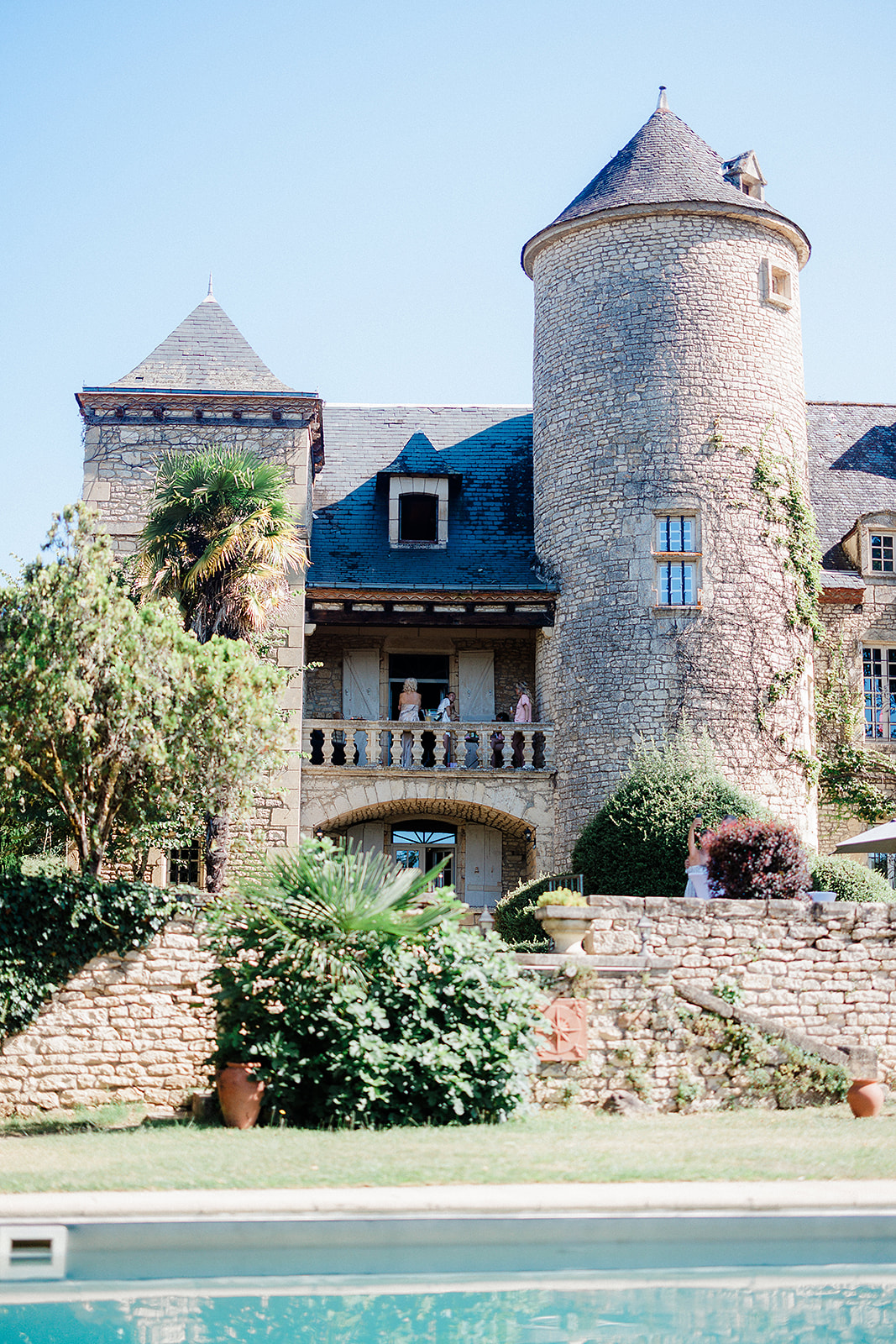 Castle wedding venue with stone towers and swimming pool in foreground