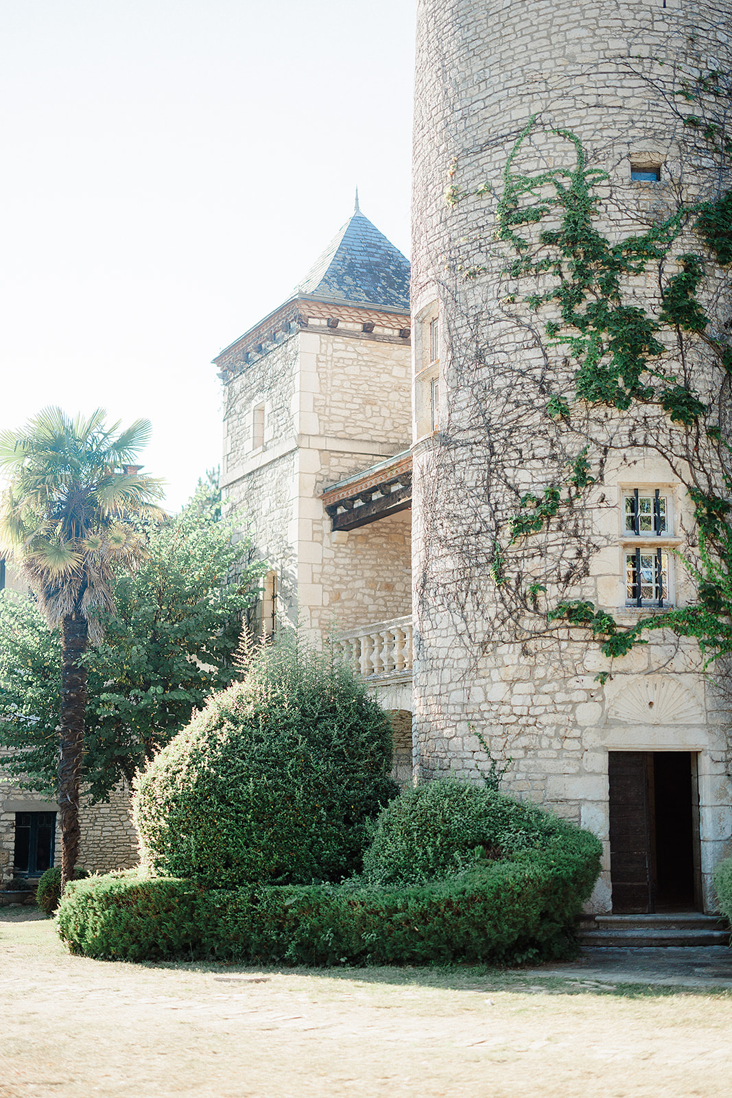 Historic château courtyard with stone tower and ivy-covered walls at French wedding venue