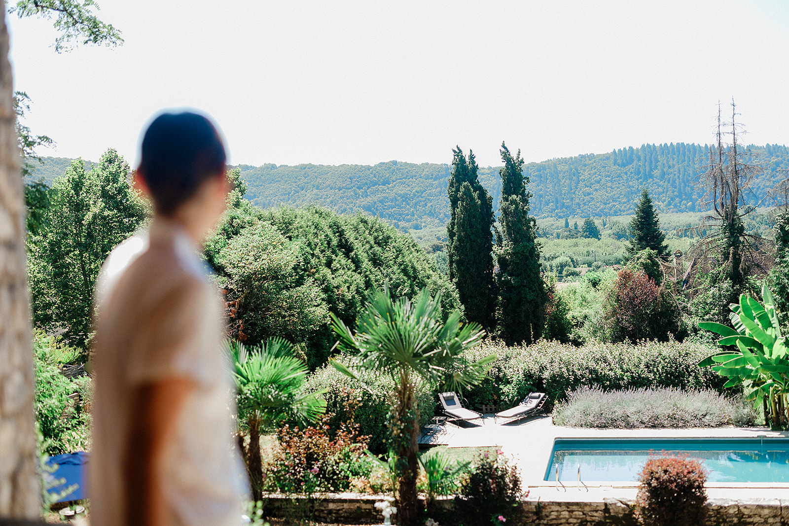 Bride in white dress overlooking gardens from poolside terrace at Tuscan villa wedding venue