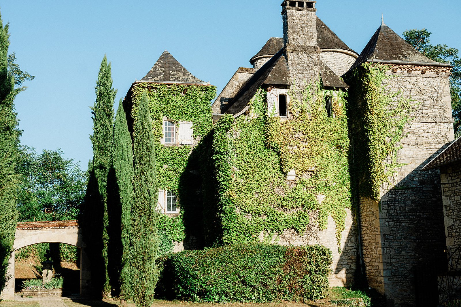 Historic stone château with ivy-covered walls and cypress trees at French wedding venue