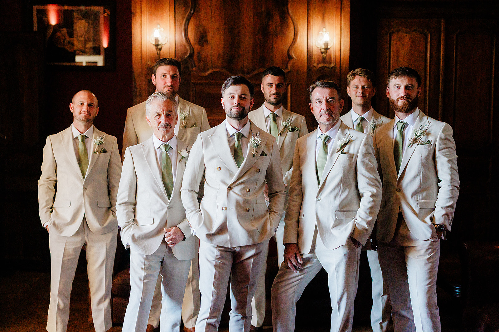 Groom and groomsmen formal portrait in elegant wood-paneled interior with sage green ties