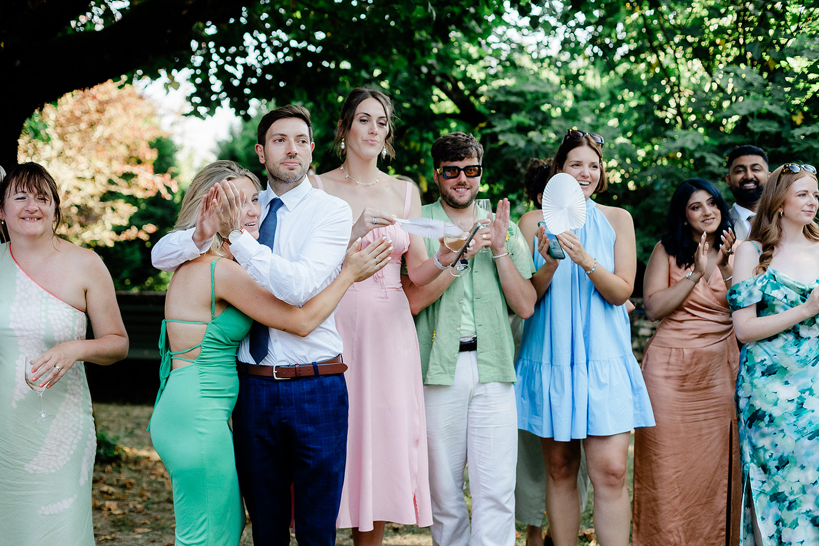 Wedding guests enjoying cocktail hour in garden setting with bride and groom
