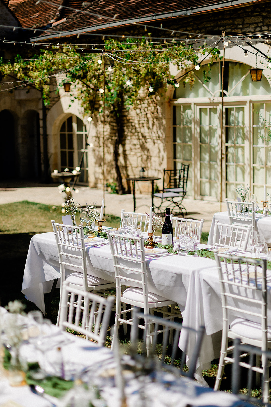 Outdoor reception table setup with white linens and hanging lights in Mediterranean stone courtyard venue