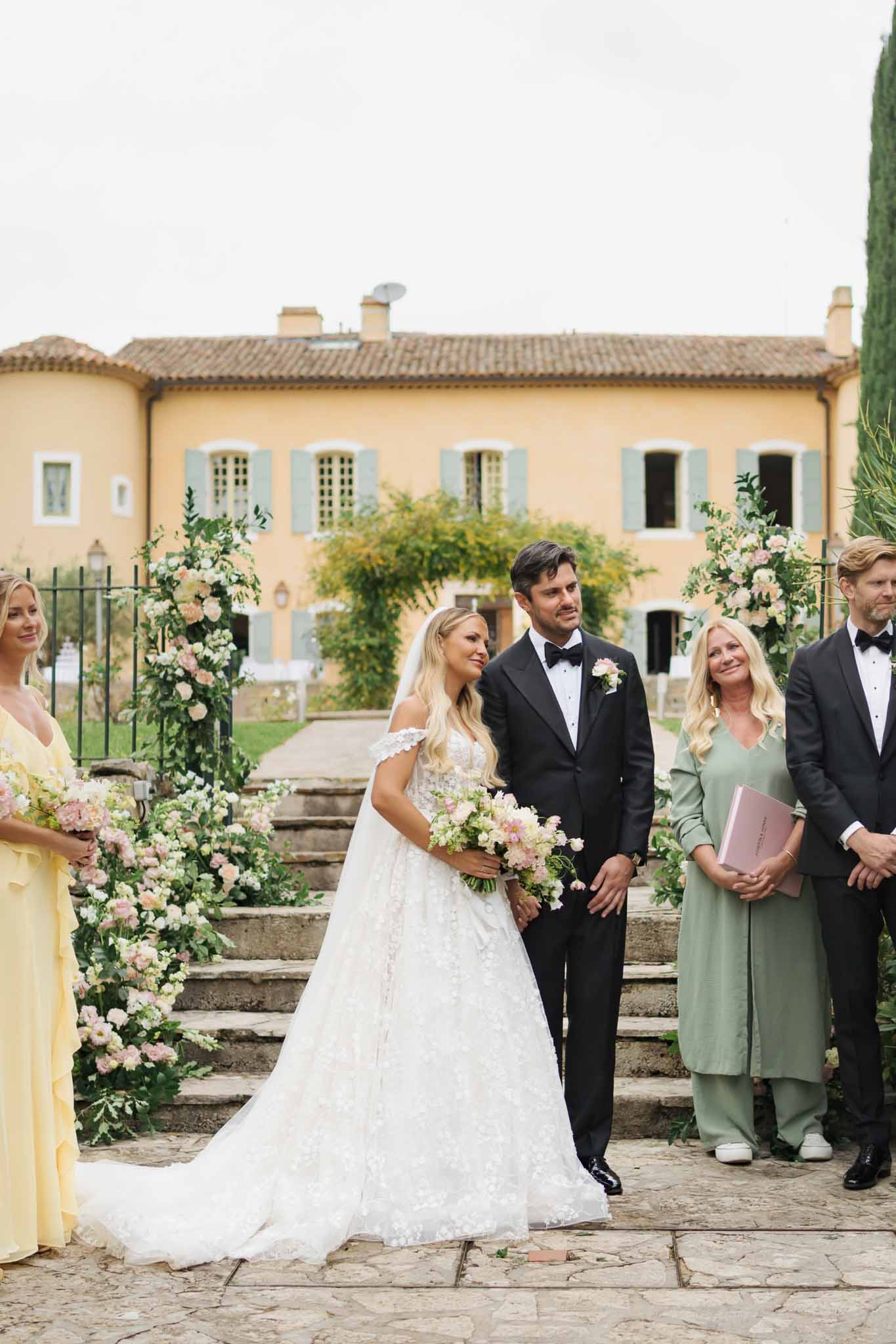 Bride and groom during wedding ceremony in Tuscan villa courtyard with floral archway