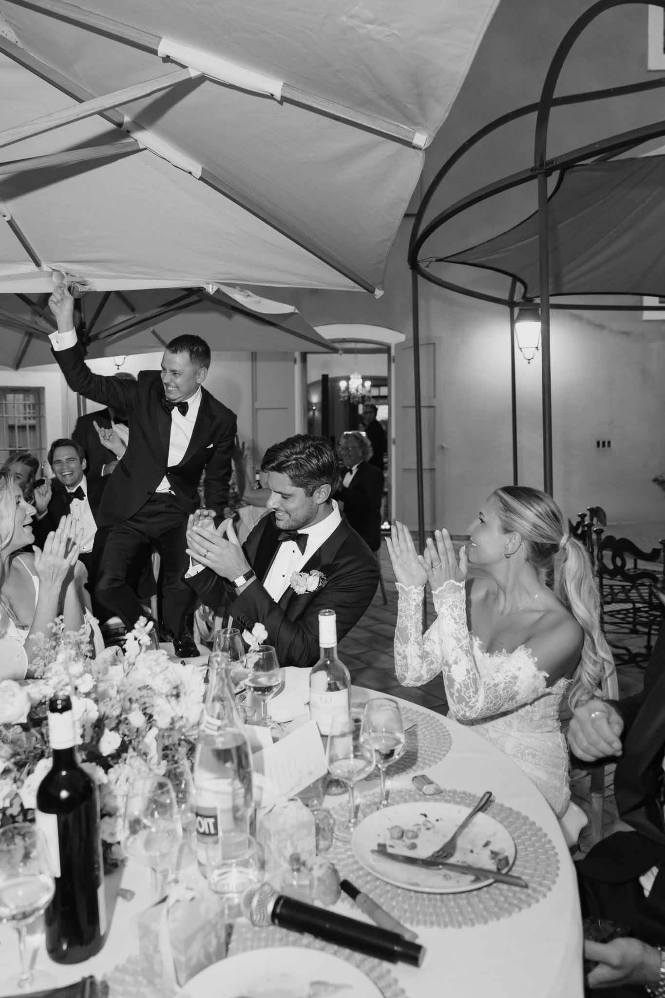 Best man giving toast at formal reception dinner under tent with bride and groom at head table