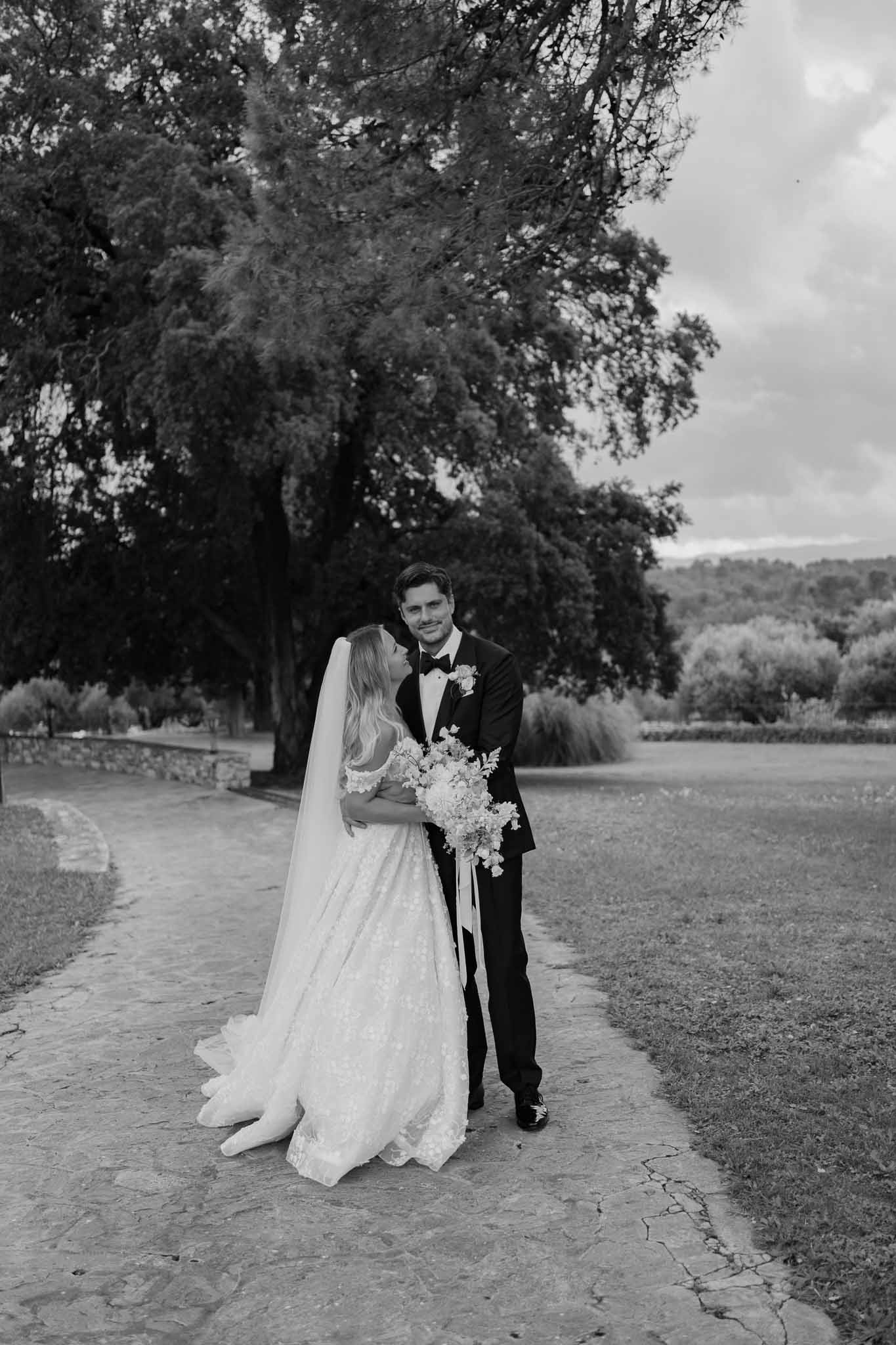 Bride and groom portrait on stone pathway in garden with weeping willow trees