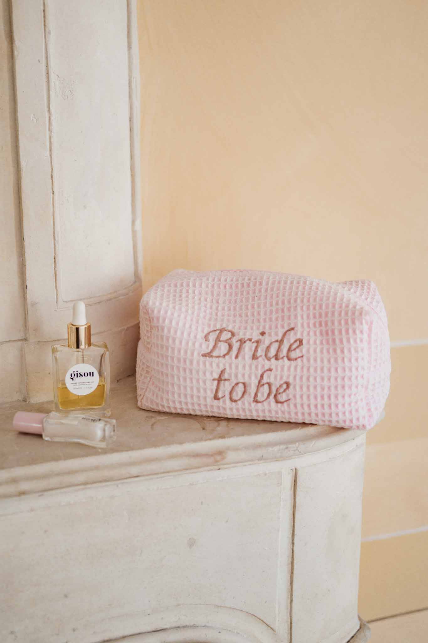 Bridal getting ready accessories arranged on wooden dresser with perfume and cosmetic bag