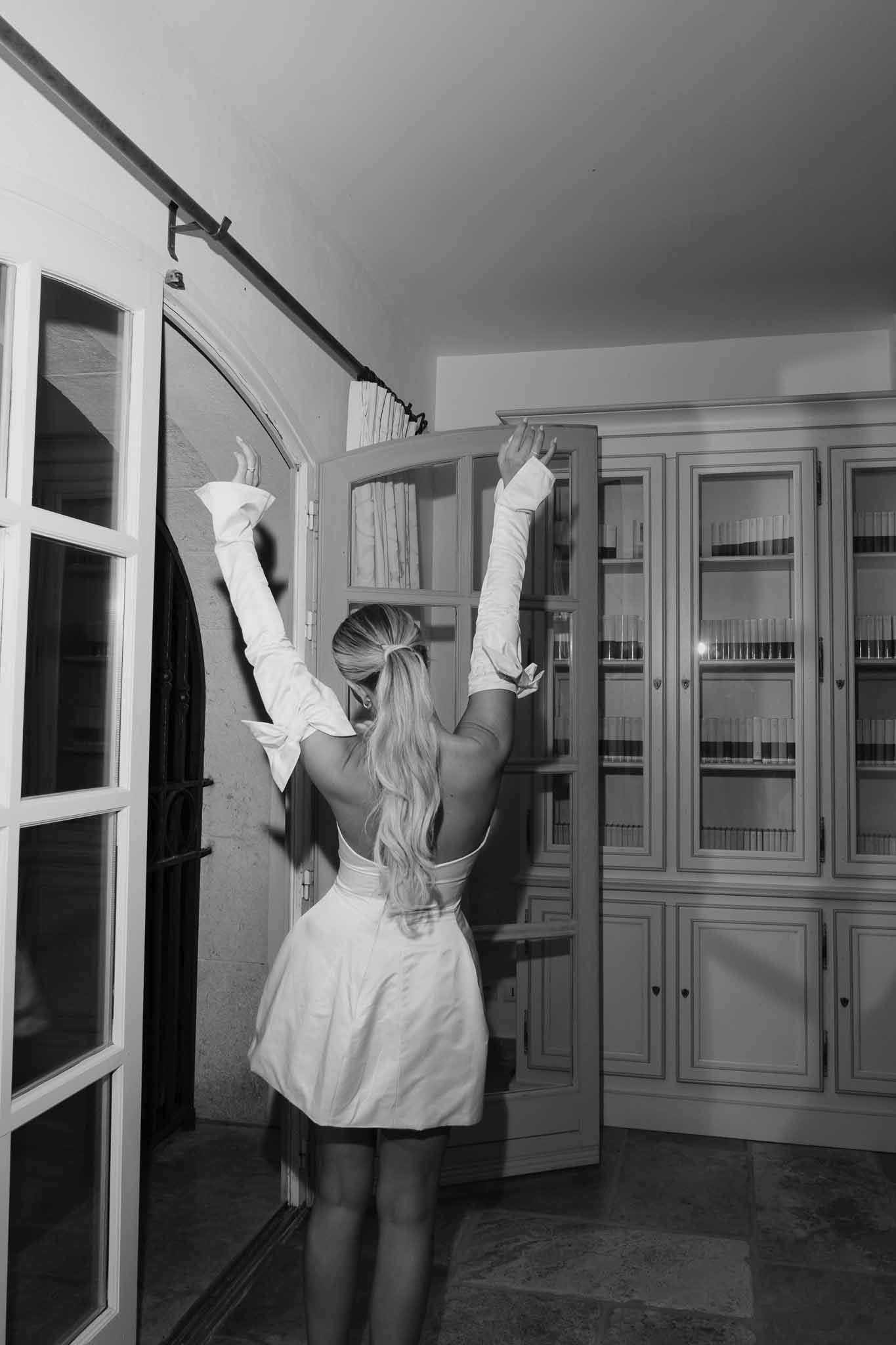 Bride celebrating in white dress and gloves during getting ready in classic interior bedroom