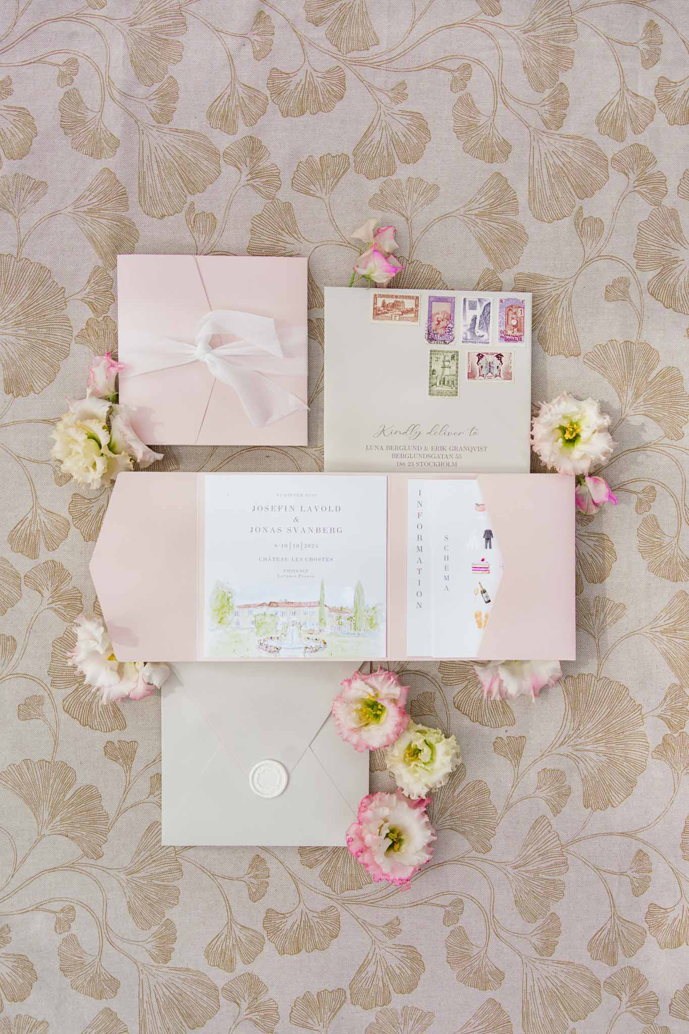 Wedding invitation suite with blush box and cream stationery displayed with pink peonies on patterned wallpaper
