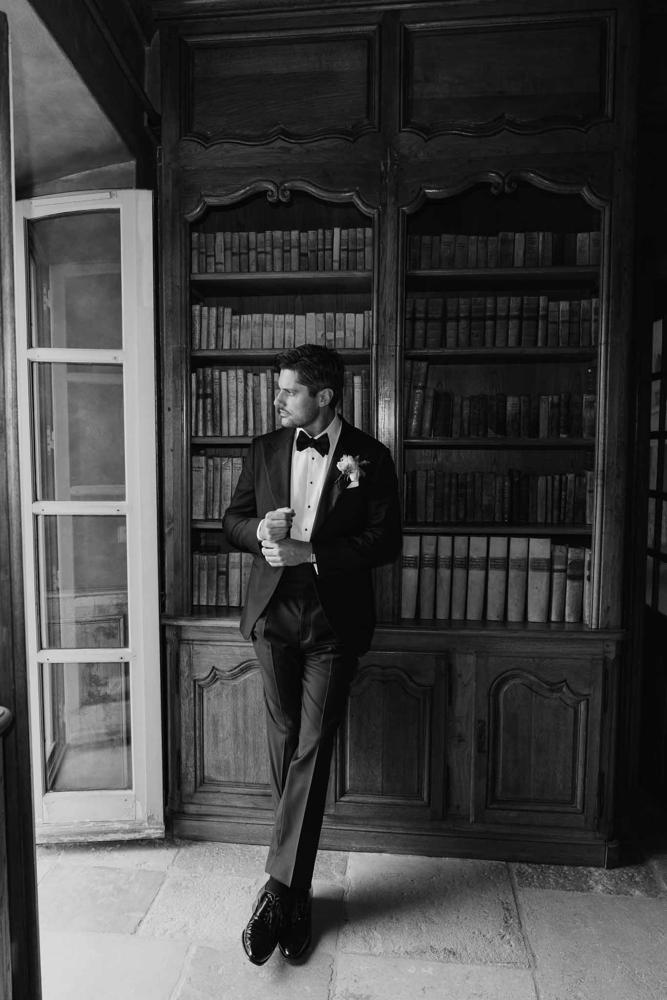 Groom in black tuxedo portrait in classic library interior