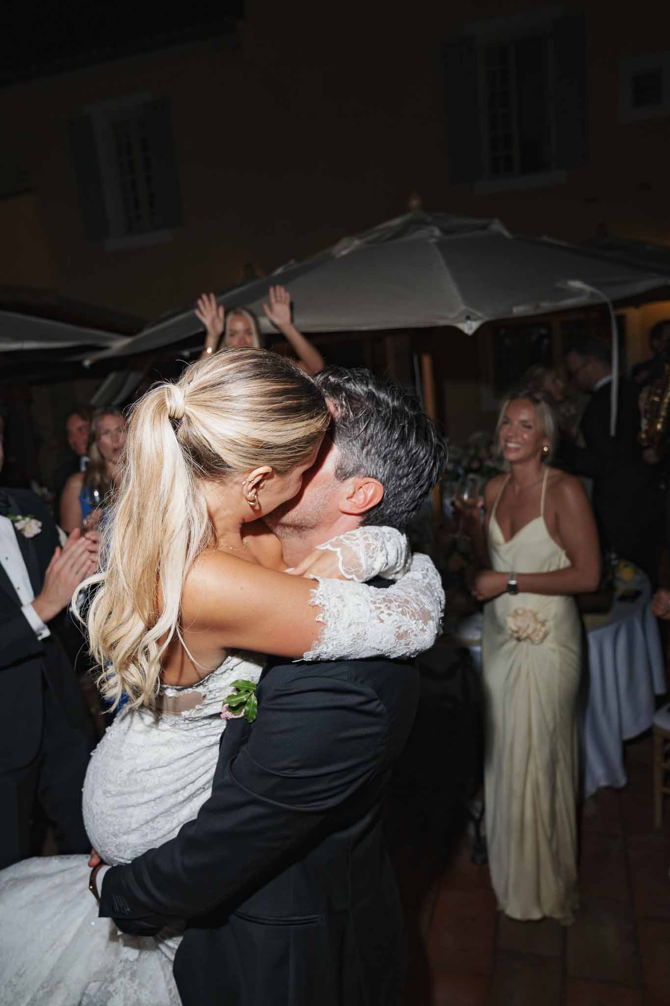 Bride and groom sharing first dance at outdoor evening wedding reception with guests watching