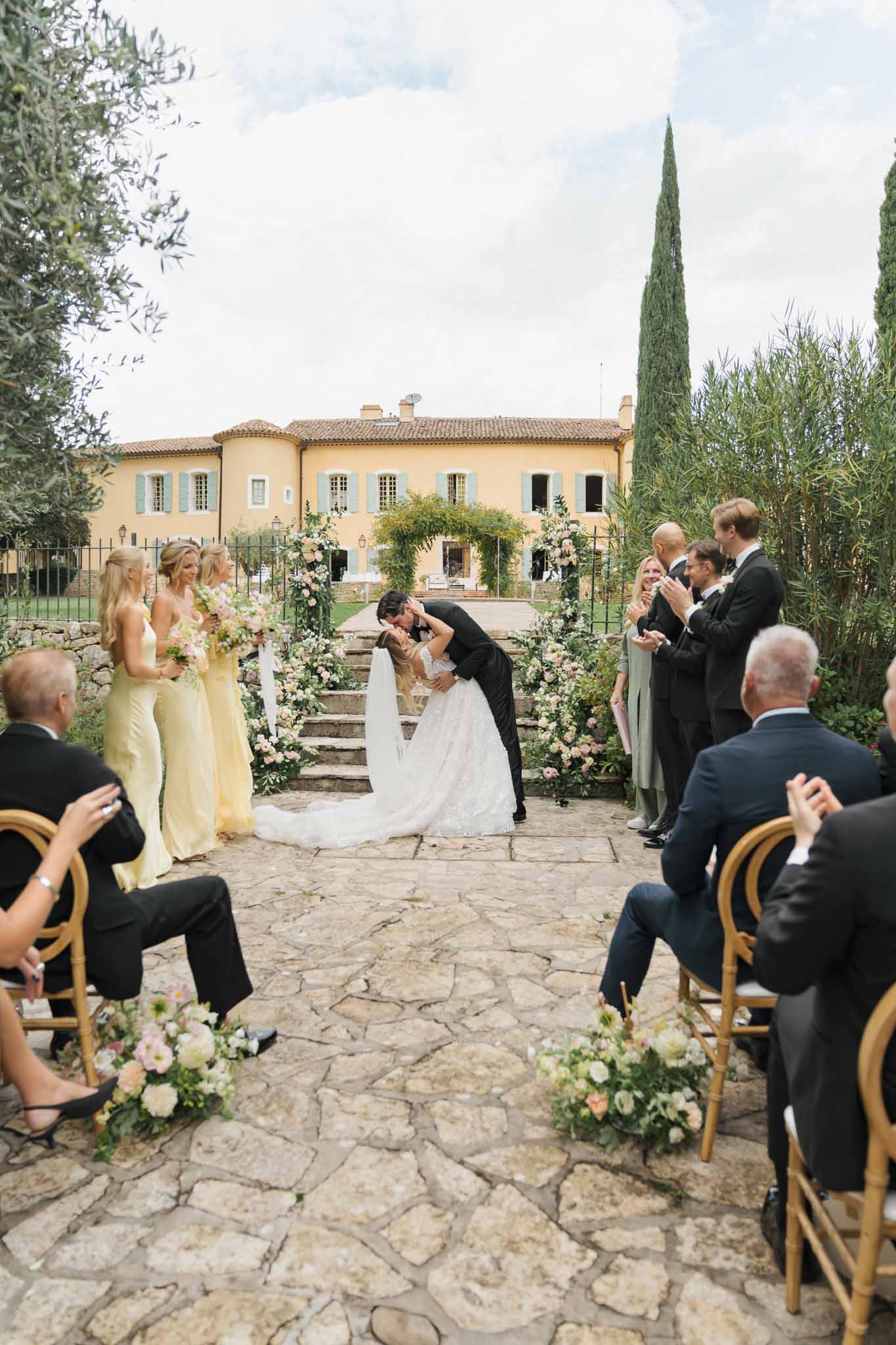Outdoor wedding ceremony kiss in Tuscan-style courtyard with ochre villa backdrop