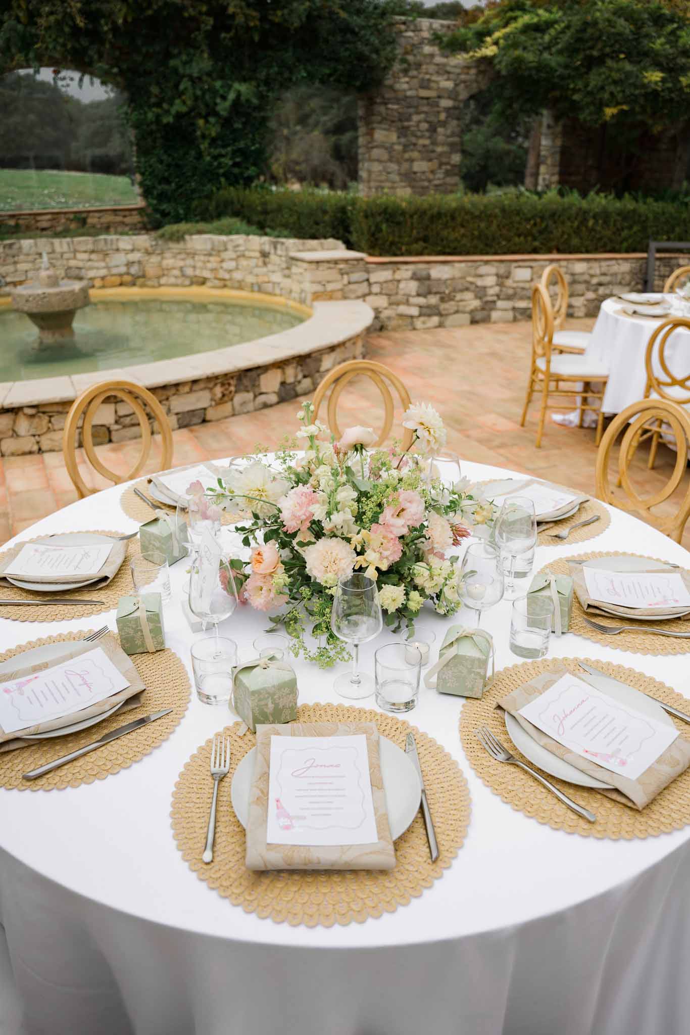 Reception table setting with pink florals and gold chairs on stone terrace at historic venue