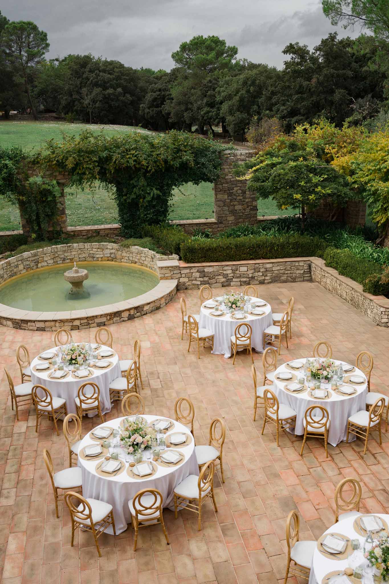 Aerial view of reception tables in stone courtyard with fountain at wedding venue