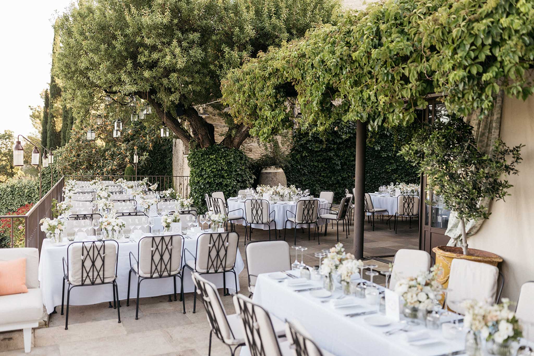 Reception terrace setup with round tables and ivy-covered stone walls at outdoor wedding venue