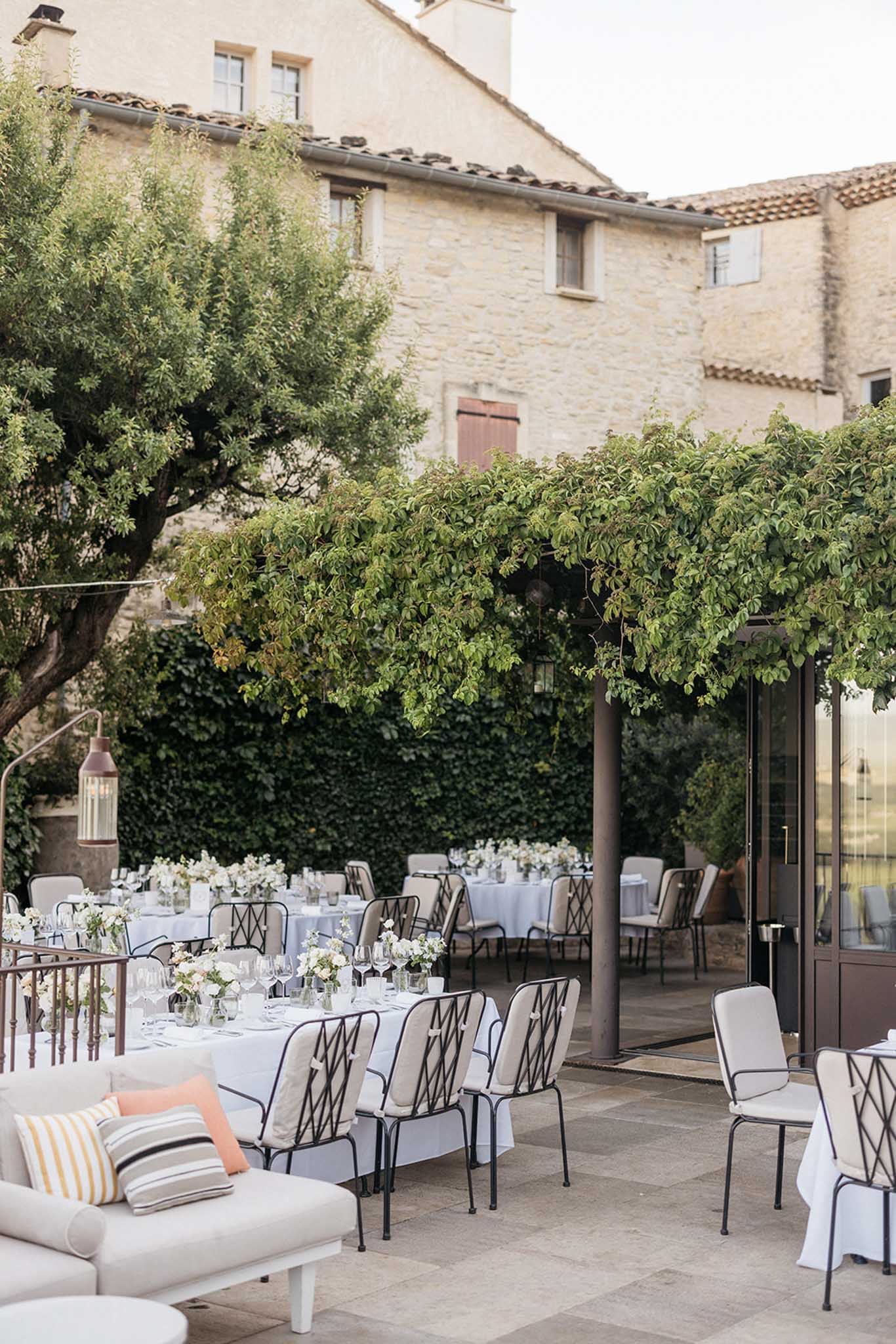 Stone courtyard reception setup at Mediterranean-style venue with white linens and flower arrangements