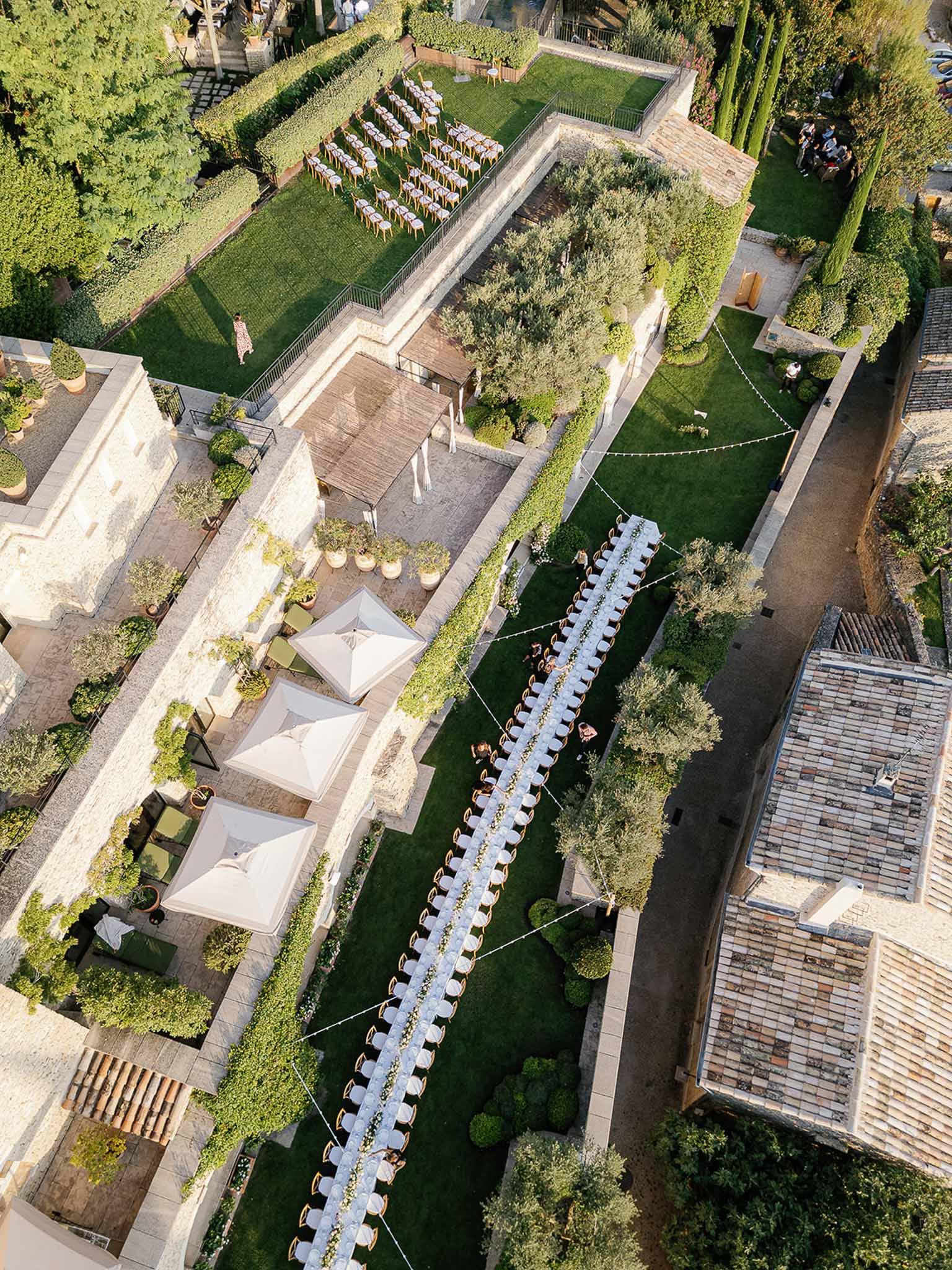 Aerial view of wedding ceremony and reception setup on garden terraces at European estate venue