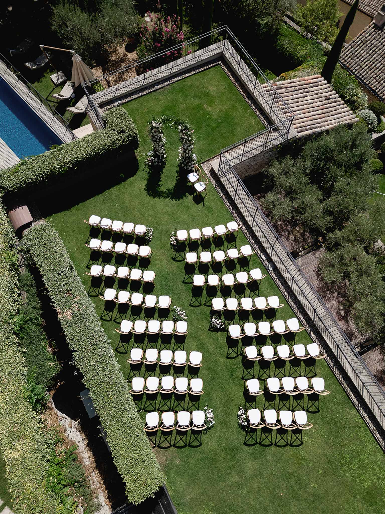 Aerial view of wedding ceremony setup in private garden courtyard with white chairs and floral arrangements