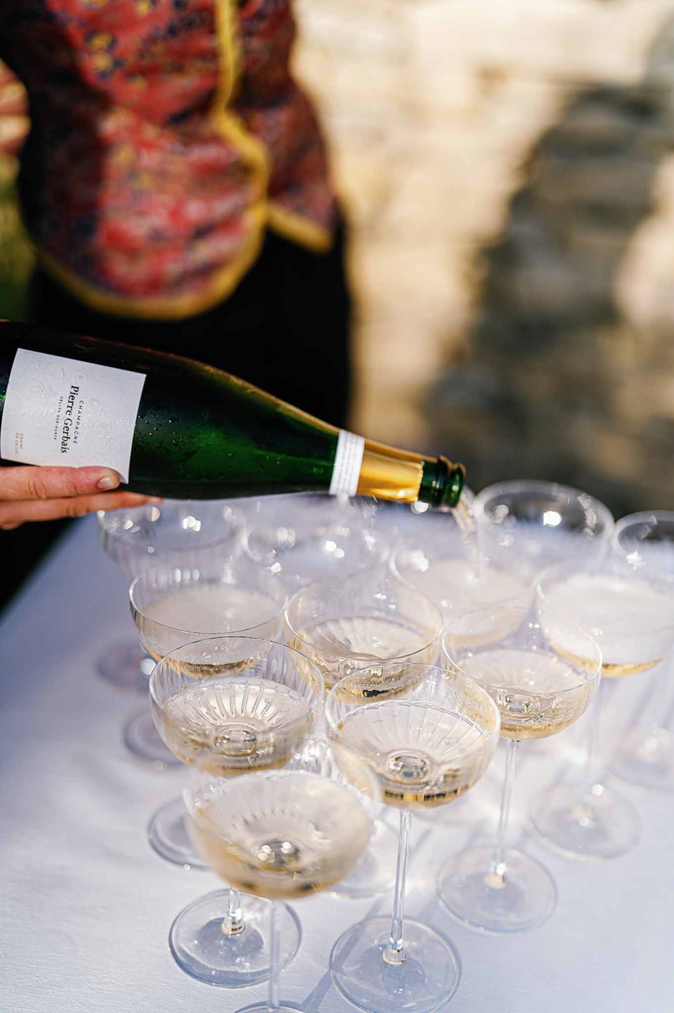 Champagne being poured into coupe glasses during outdoor cocktail hour at historic venue