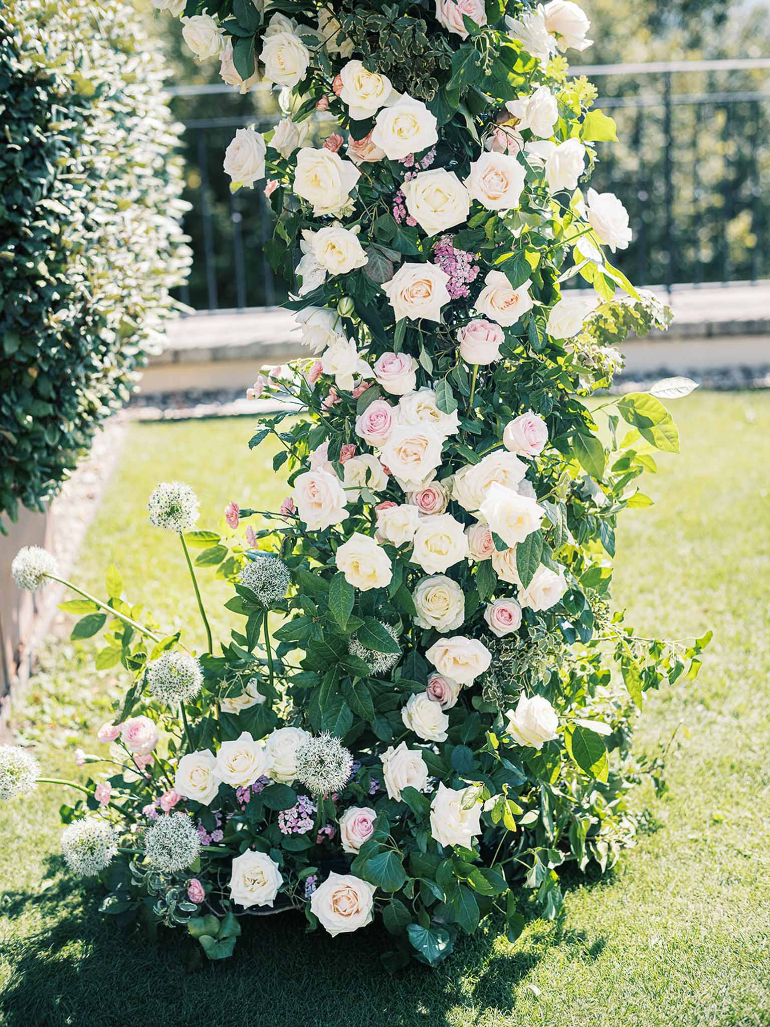 Cascading floral arrangement with cream and blush roses in formal garden setting