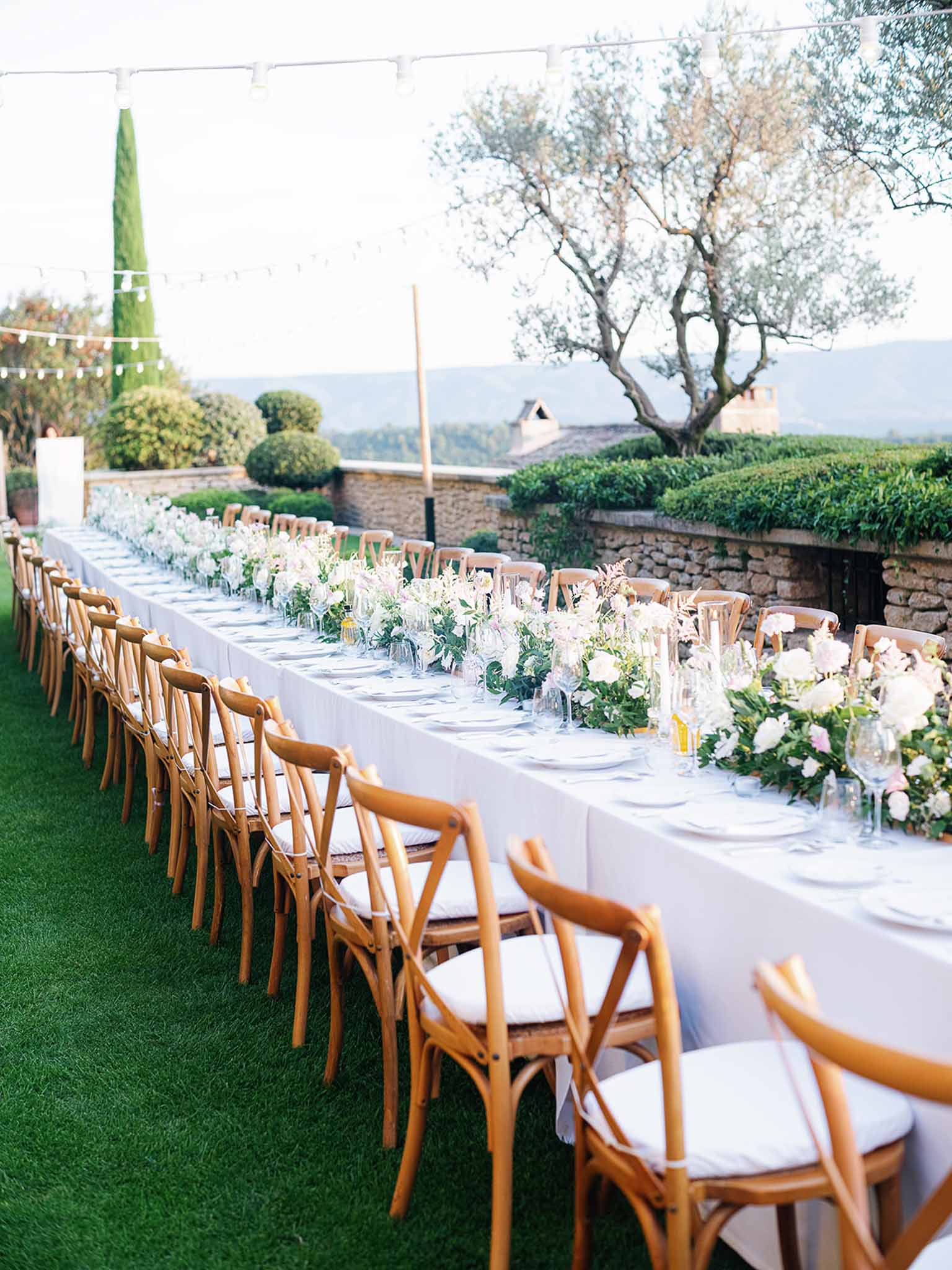 Long outdoor reception table with white linens and floral runner at Mediterranean garden wedding venue