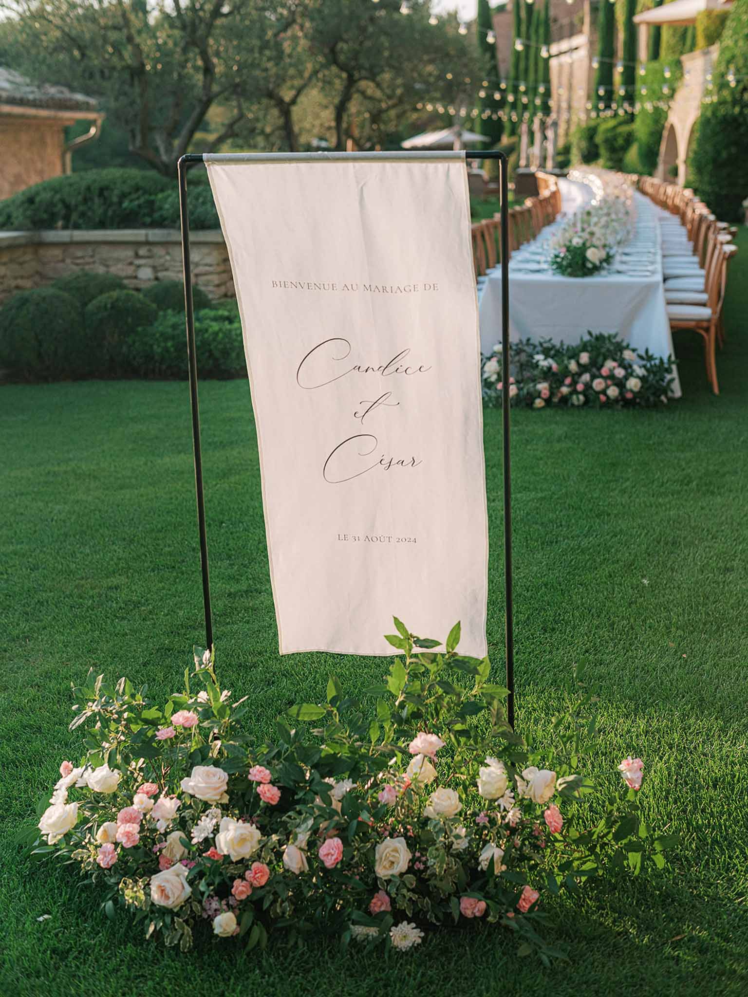 Wedding reception entrance banner and table setting in formal garden with floral arrangements