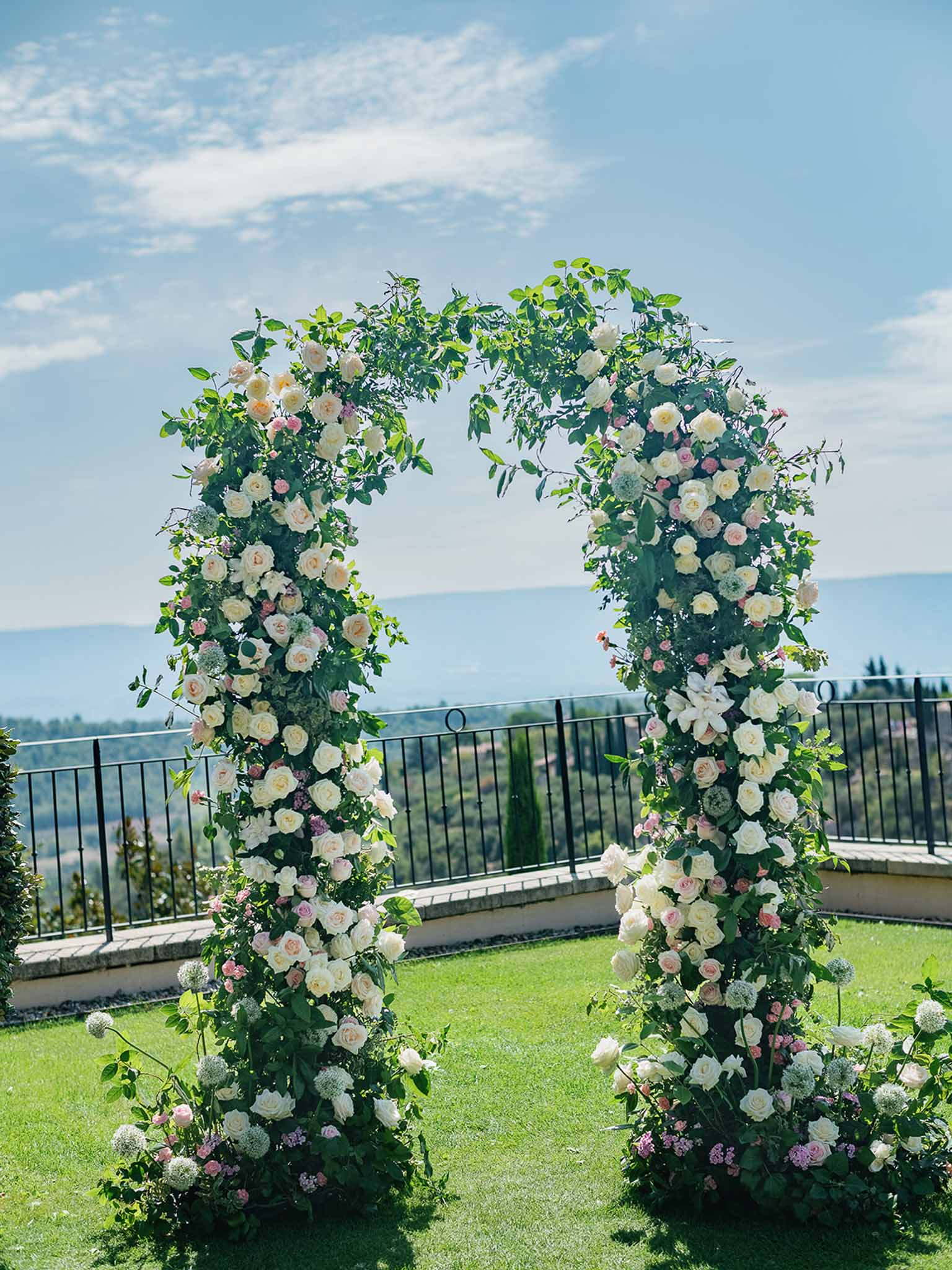 Floral ceremony arch with roses and hydrangeas at lakeside wedding venue