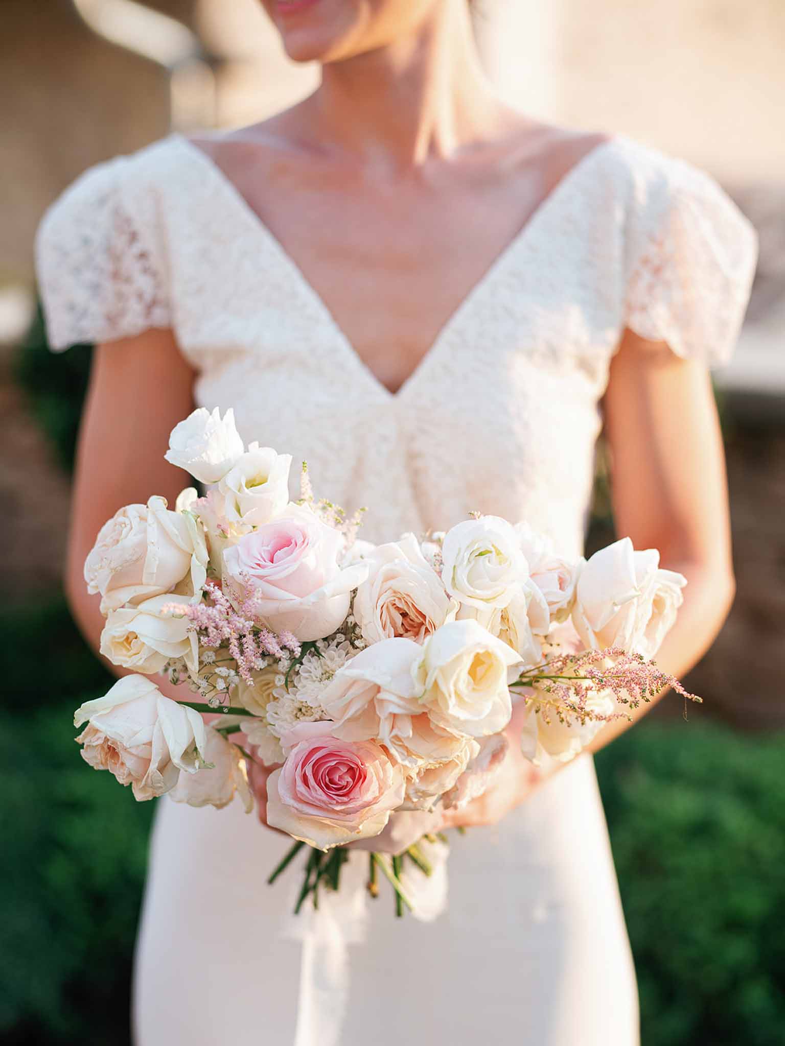 Bride holding garden-style bouquet with ivory and blush roses outdoors