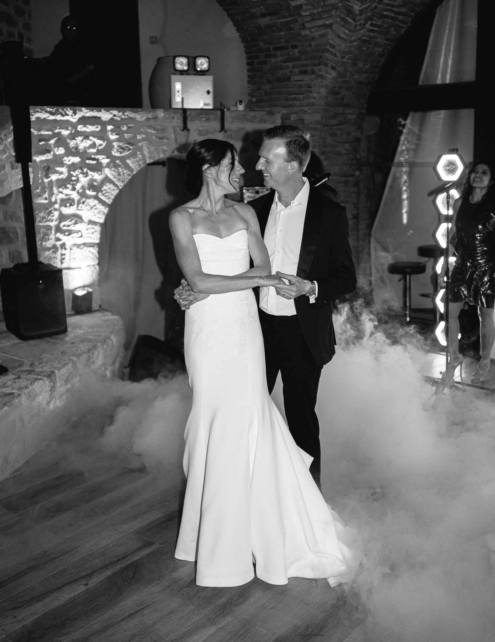 Couple's first dance with fog effects in stone venue with arched brick ceilings