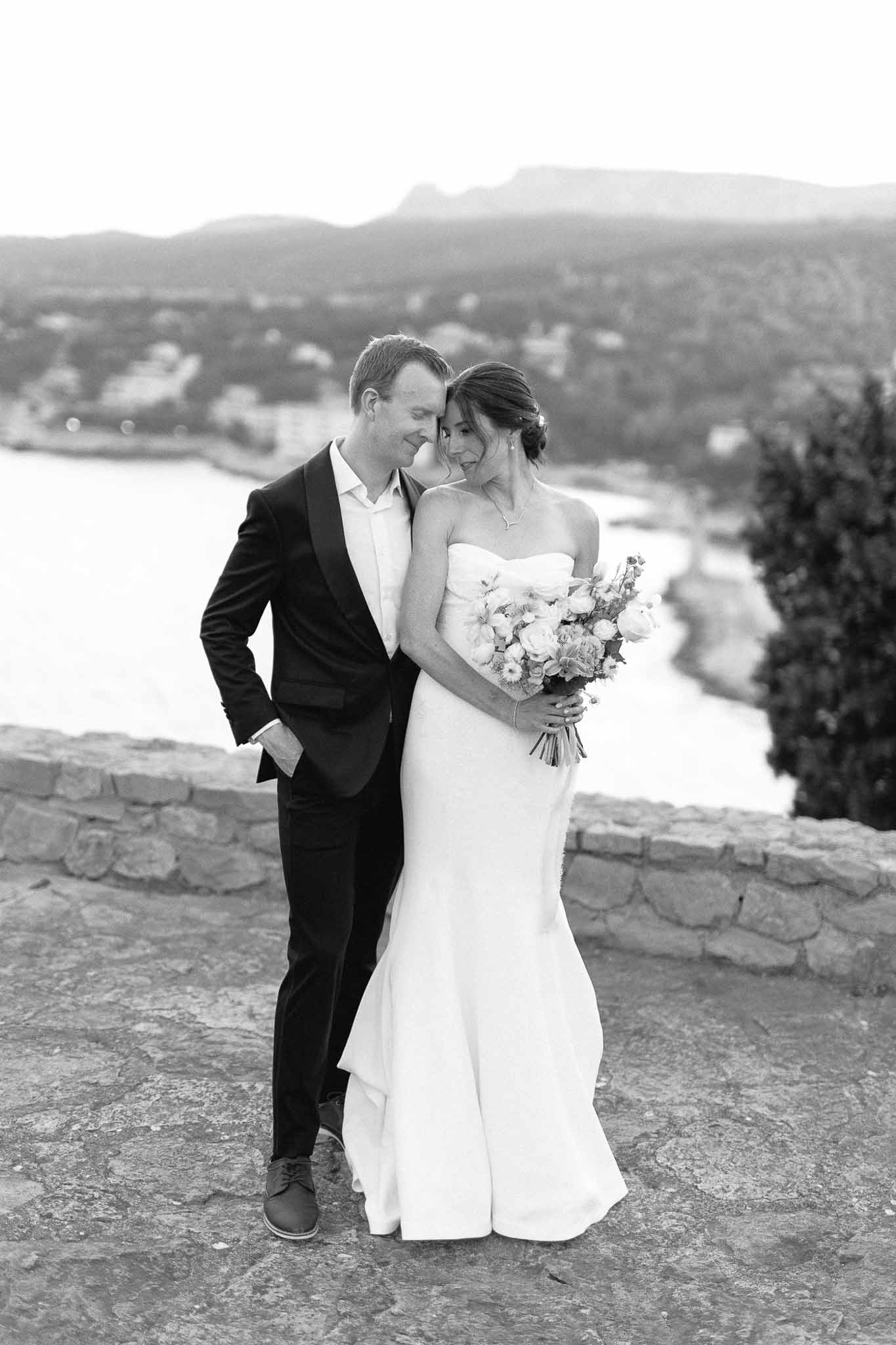 Black and white bridal portrait of couple on stone terrace overlooking valley landscape