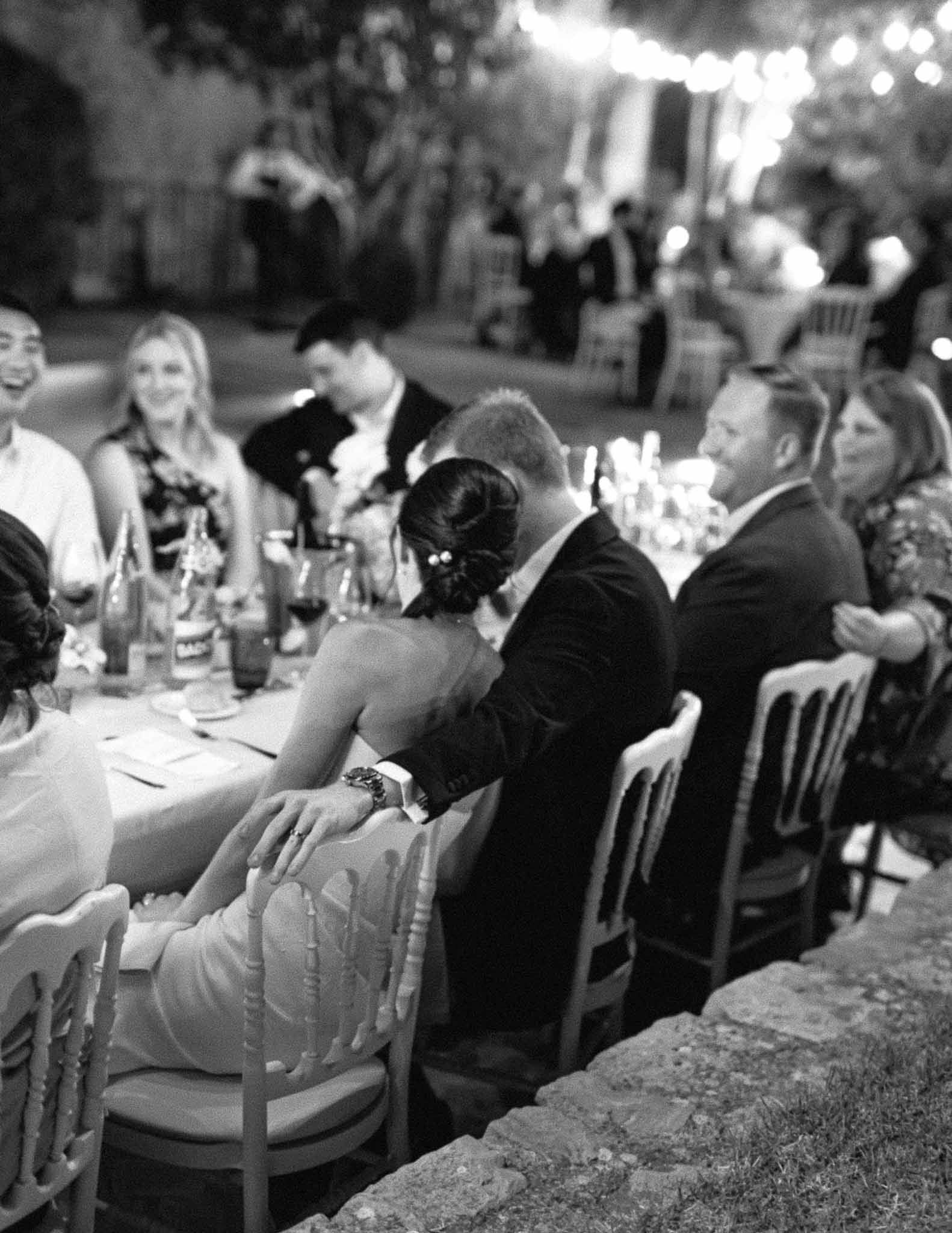 Outdoor reception dinner with guests seated at long banquet table in garden courtyard venue