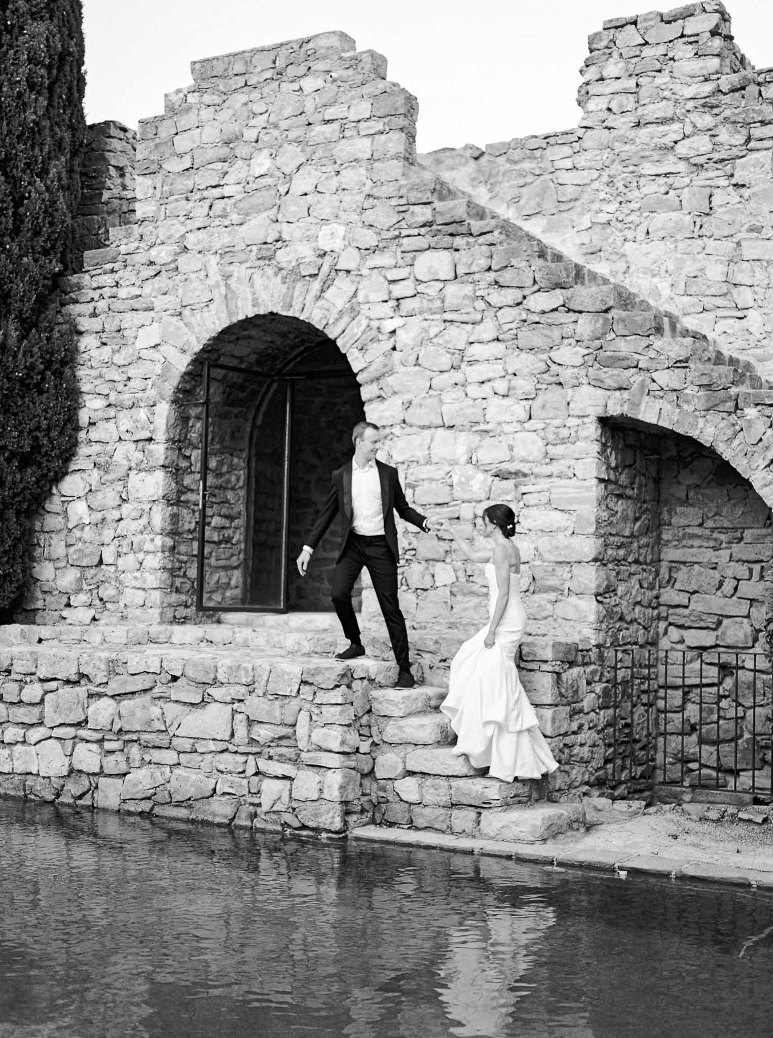 Bride and groom portrait at historic stone ruins beside water